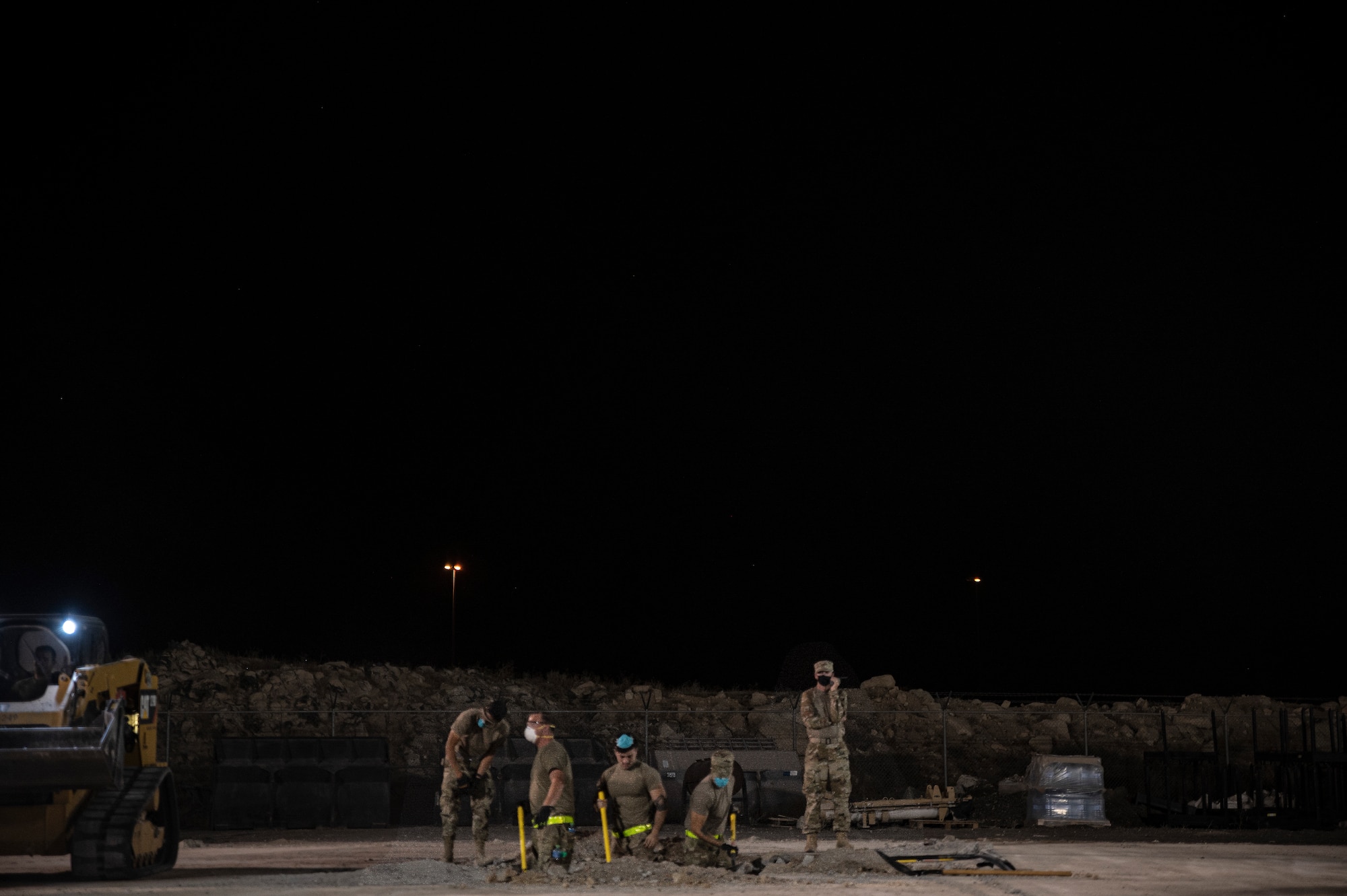 Airmen shovel out dirt from a hole.