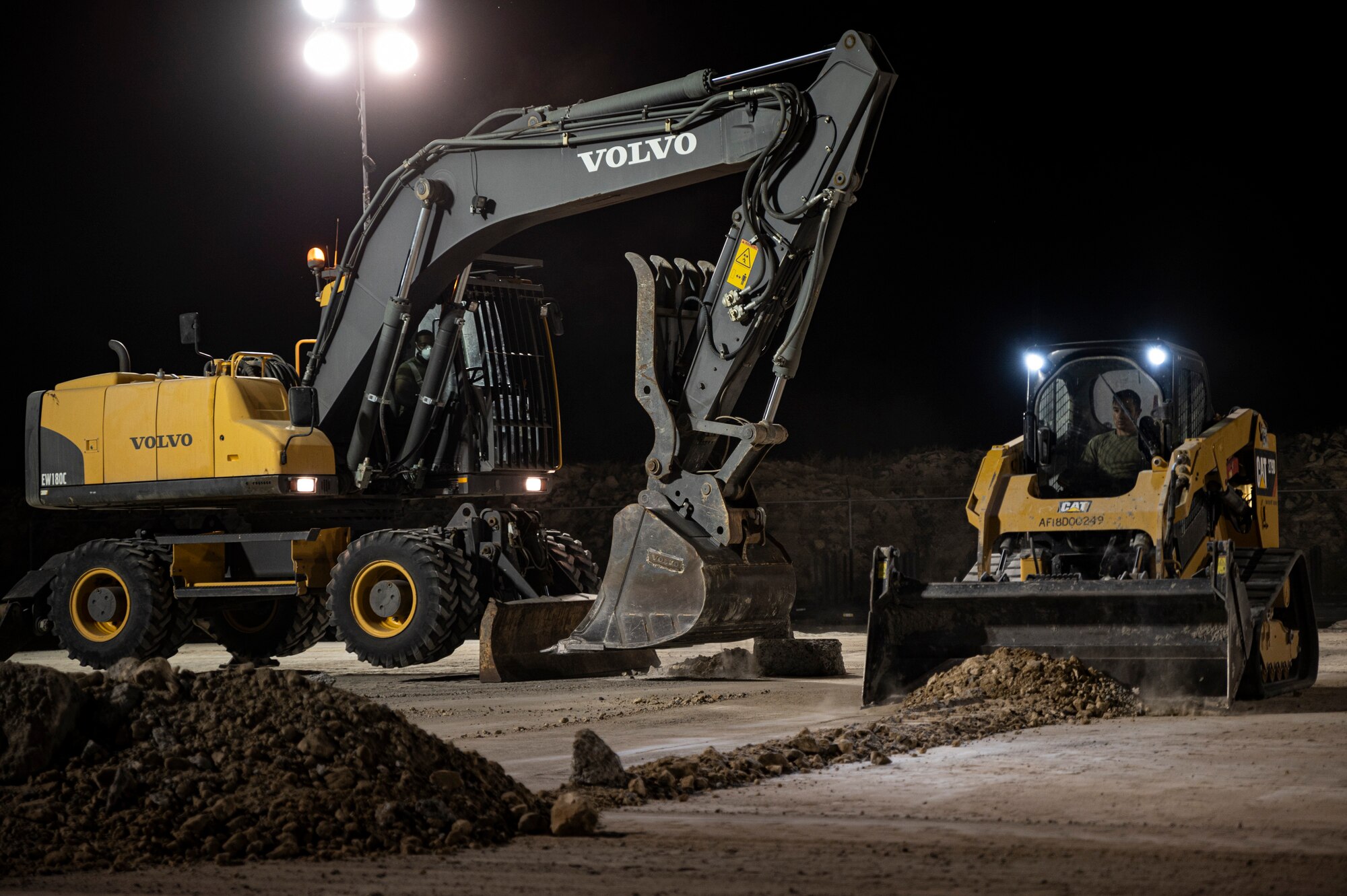 Construction vehicles dig up and move debris from a construction site.