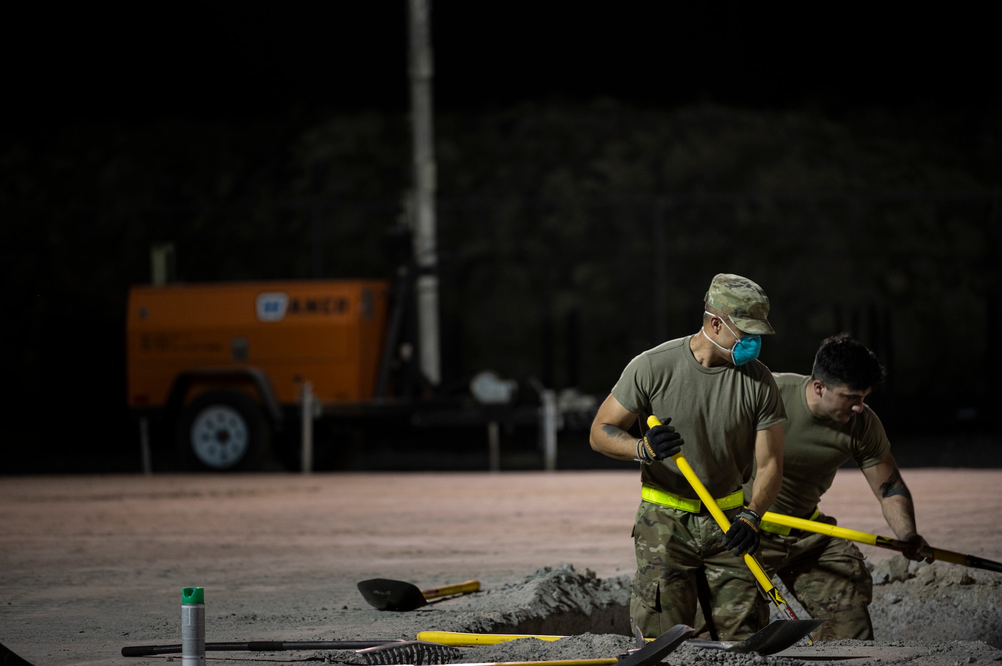 Airmen shovel dirt from a hole.