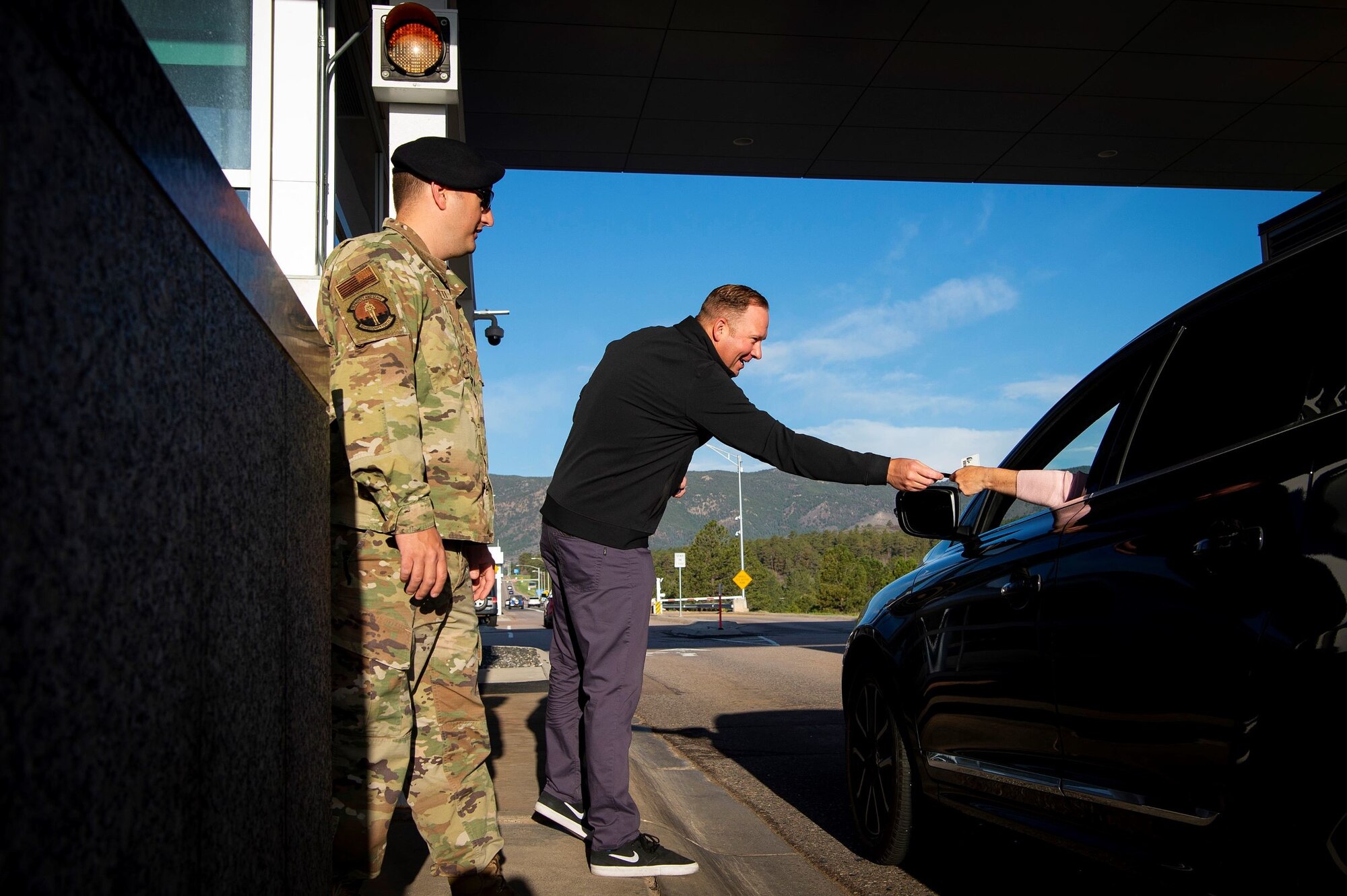 Nate Pine, the Air Force Academy’s athletics director, assists Airmen from the 10th Security Forces Squadron check the identification of drivers traveling through the north gate, May 20, 2021.