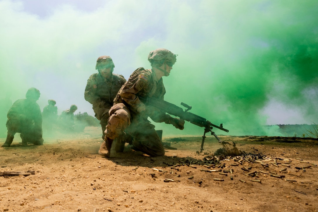 A group of soldiers holding weapons kneel on dusty ground as green smoke swirls around them.