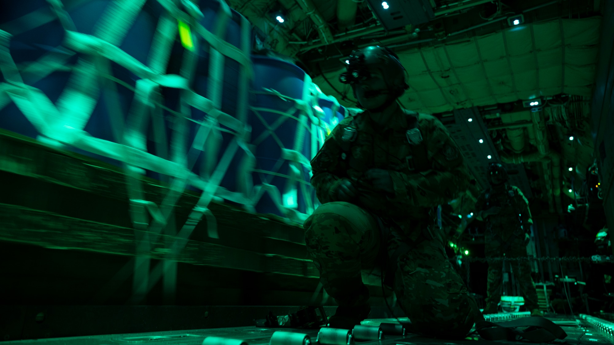 A loadmaster cuts the restraint of a container delivery system