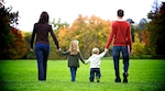 A family walking away holding hands in a park.