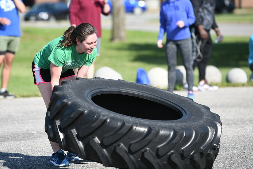 An Airman lifts a large tire while competing in a tactical fitness event during Wingman/Shipmate Day at Joint Base Andrews, Md., May 11, 2021. The tactical fitness event included a short run and lifting, pushing and carrying heavy weights. (U.S. Air Force photo by Airman 1st Class Bridgitte Taylor)
