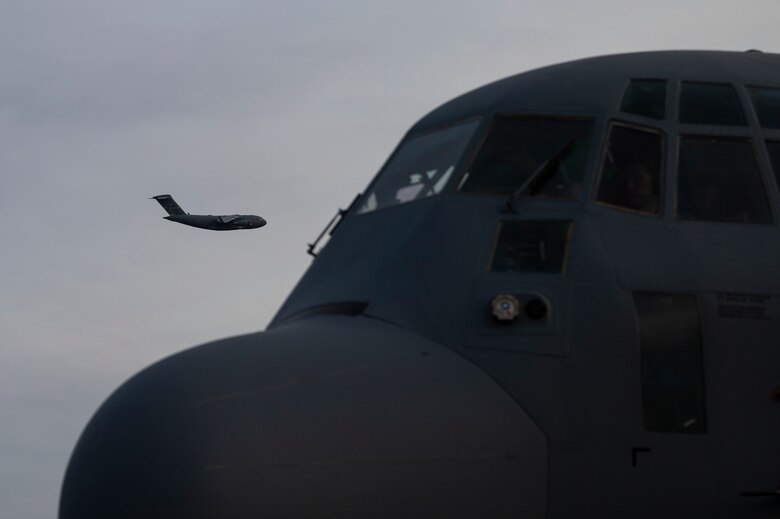 An aircraft flies above the flightline