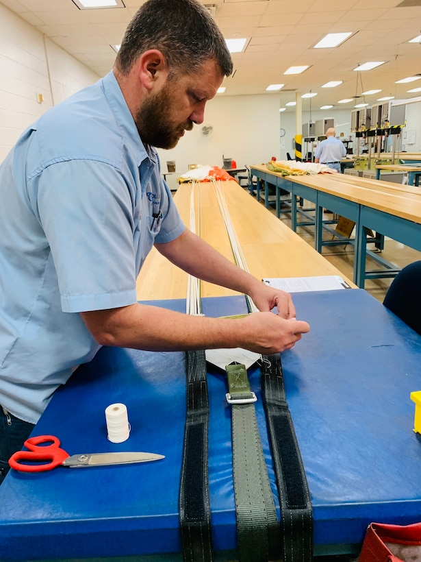 Daniel Arellano inspects connector links on the harness assembly of a parachute