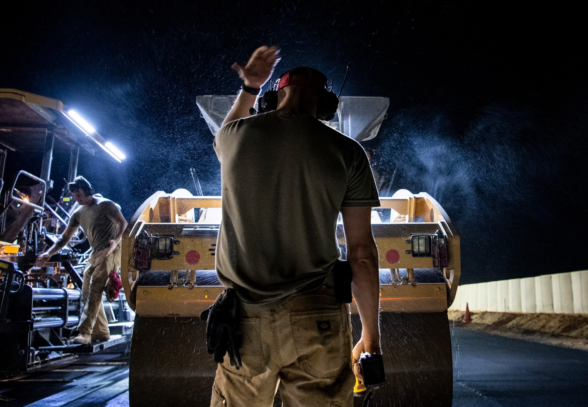 A REDHORSE Airman guides a steam roller on freshly paved asphalt, at Air Base 201, Agadez, Niger. RED HORSE airmen had to overcome extreme heat, dust storms, plagues of locusts, and flash floods to build the largest Air Force led construction project in Air Force history. (U.S. Air Force photo by Tech. Sgt. Perry Aston)
