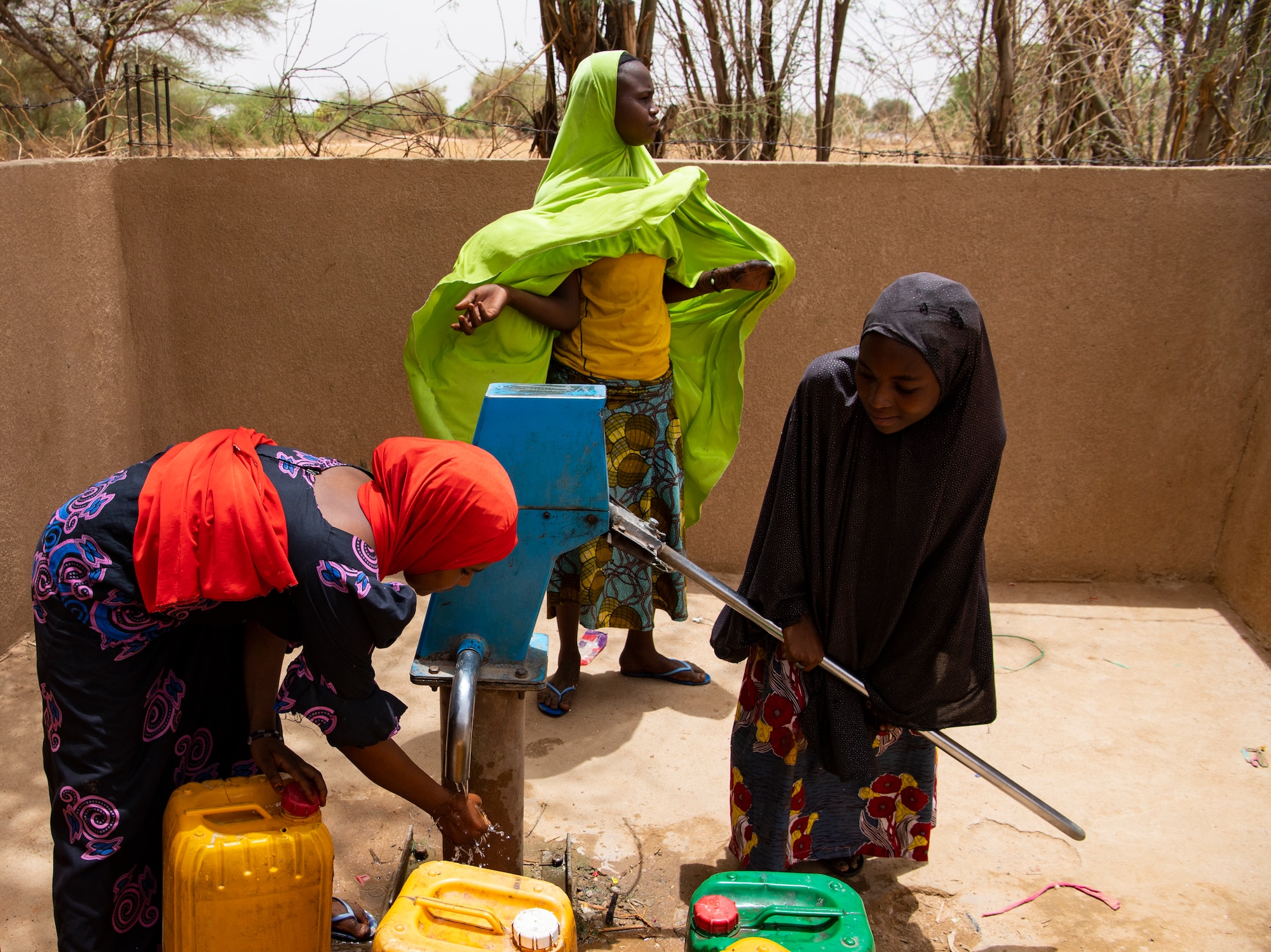 Nigerien women pump water into containers at the village well. The well is currently being converted into a solar powered well, to eliminate the need to hand pump water. (U.S. Air Force photo by Tech. Sgt. Perry Aston)
