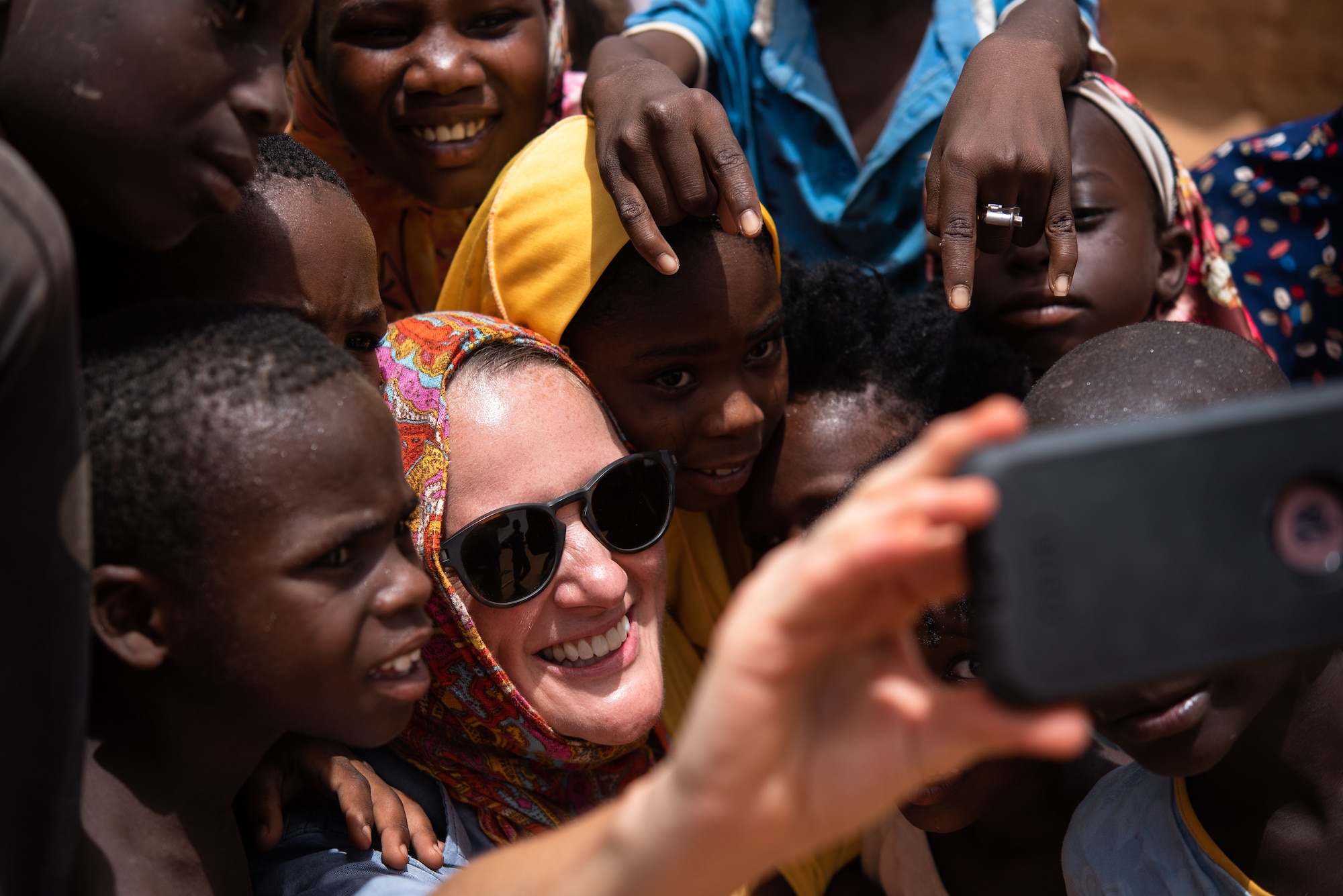 U.S. Army Staff Sgt. Cana Garrison, Civil Affairs Team 204, takes a selfie with Nigerien children at a village in Agadez, Niger, June 27, 2019. The civil affairs team reaches out to the local community on a weekly basis to strengthen the relationship between the Nigeriens and the U.S. military. (U.S. Air Force photo by Staff Sgt. Devin Boyer)