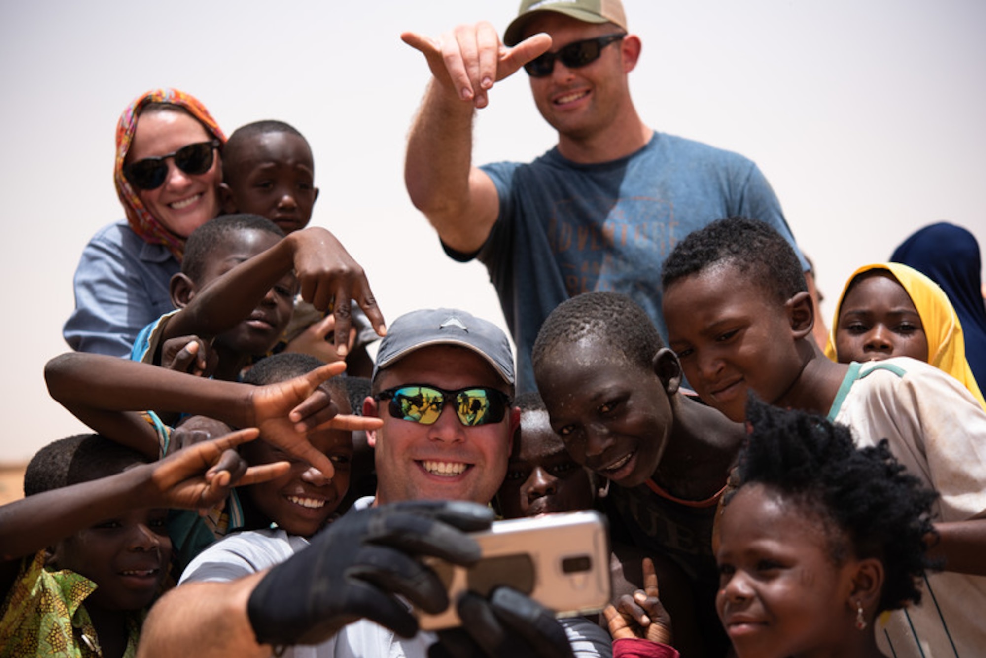 U.S. Air Force Staff Sgt. Jacob Johnson, 435th Air Expeditionary Wing chaplain assistant, takes a selfie with Nigerien children at a village in Agadez, Niger, June 27, 2019. Johnson assisted the 724th Expeditionary Air Base Squadron civil engineer flight with constructing a classroom for the village. (U.S. Air Force photo by Staff Sgt. Devin Boyer)