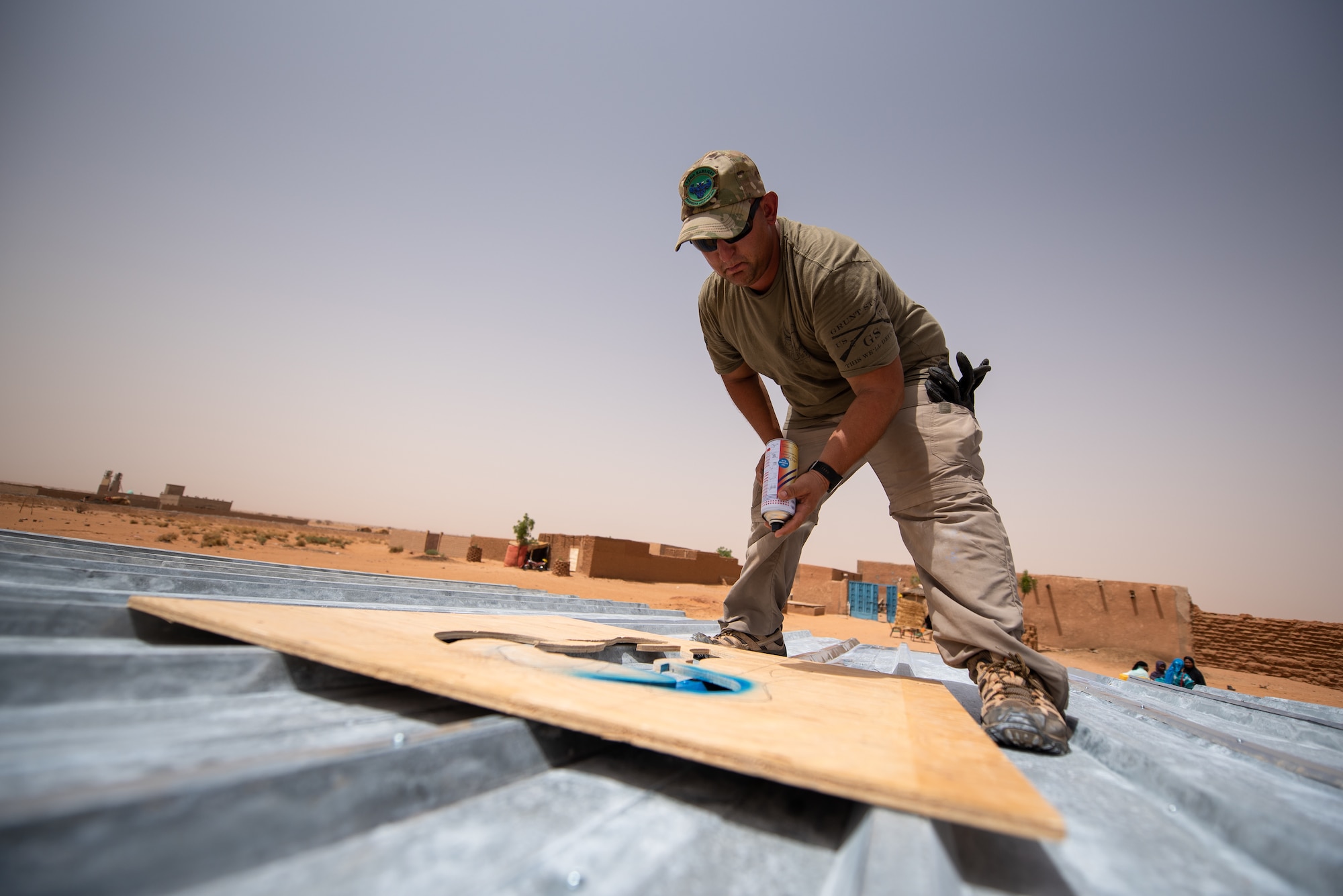 U.S. Air Force Tech. Sgt. Kelly Warren, 724th Expeditionary Air Base Squadron civil engineer flight structural craftsman, paints a bull head on the roof of a classroom at a village in Agadez, Niger, June 27, 2019. The civil engineers built the classroom from scratch and the bull is a symbol of the Prime Base Engineer Emergency Force, or Prime BEEF. (U.S. Air Force photo by Staff Sgt. Devin Boyer)