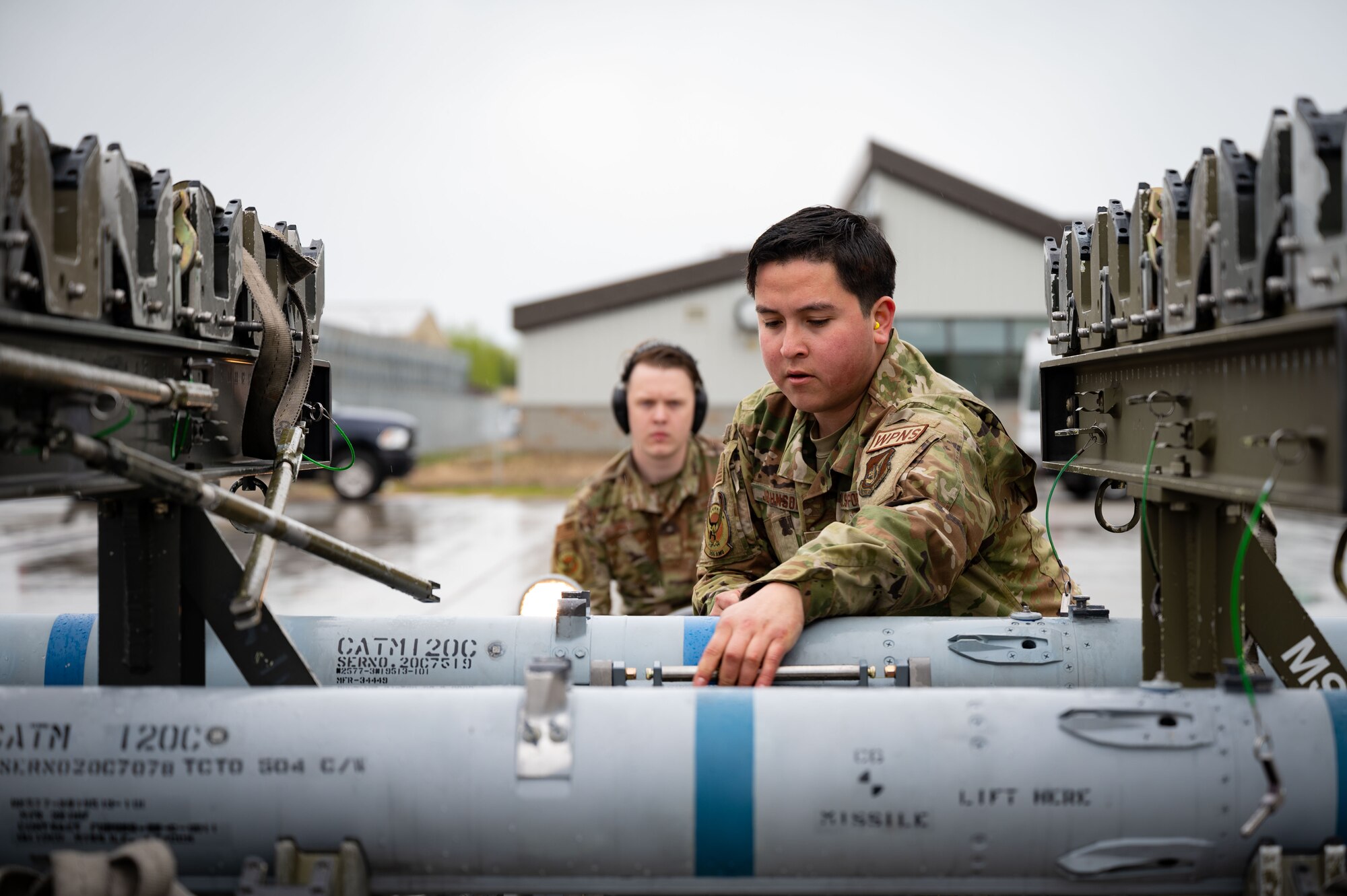 U.S. Air Force Staff Sgt. Andrew Johnson, a 355th Aircraft Maintenance Unit (AMU) weapons load crew chief, and Senior Airman Trever Nichols, a 355th AMU weapons load crew member, pick up an AIM-120 during a load competition on Eielson Air Force Base, Alaska, May 21, 2021.