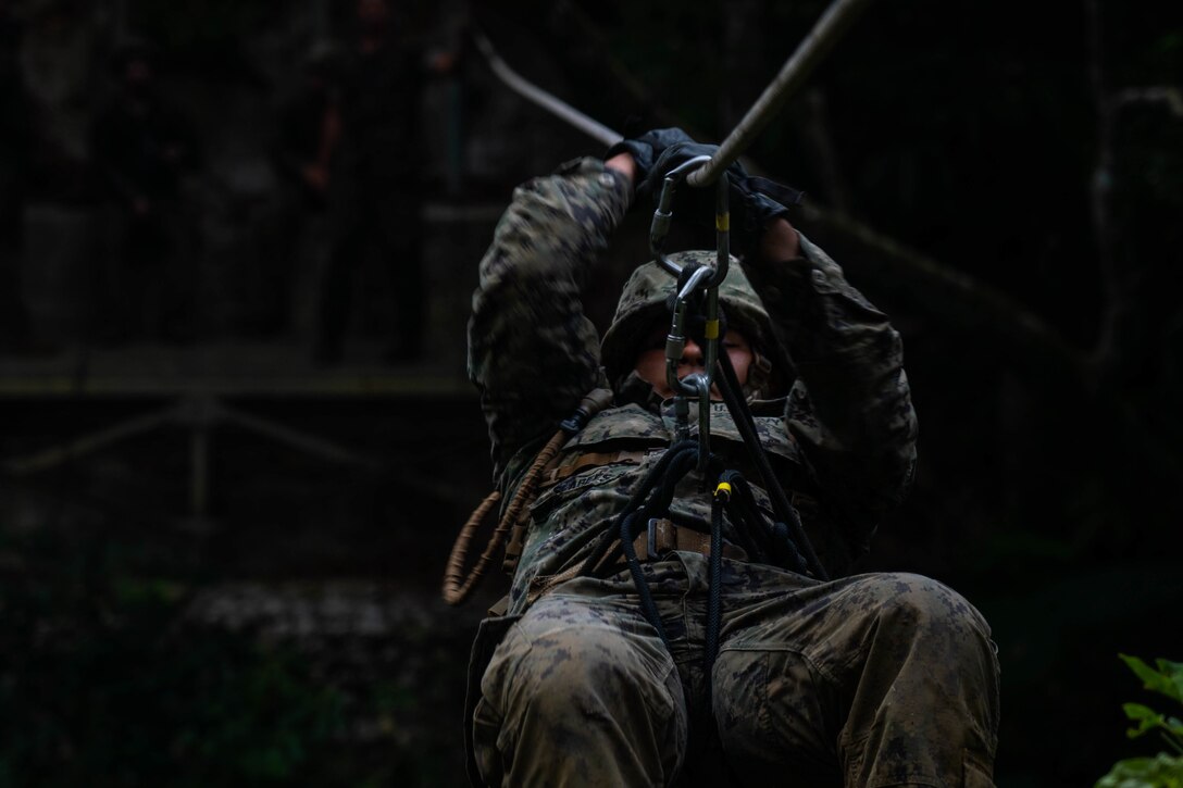 U.S. Navy Builder Carlos Hernandez with Naval Construction Battalion Four, pulls himself across a line at the Jungle Warfare Training Center during exercise Pacific Pioneer at Camp Gonsalves, Okinawa, Japan, April 15, 2021. Pacific Pioneer serves as 9th Engineer Support Battalion's Marine Corps Combat Readiness Evaluation as well as an opportunity to demonstrate the ability to establish and sustain expeditionary advanced bases with survivable force protection, practice naval integration, and position long range precision fires and tactical logistics nodes across littoral regions in support of naval operations. 3d Marine Logistics Group, based out of Okinawa, Japan, is a forward deployed combat unit that serves as III MEF’s comprehensive logistics and combat service support backbone for operations throughout the Indo-Pacific area of responsibility. (U.S. Marine Corps photo by Lance Cpl. Moises Rodriguez)