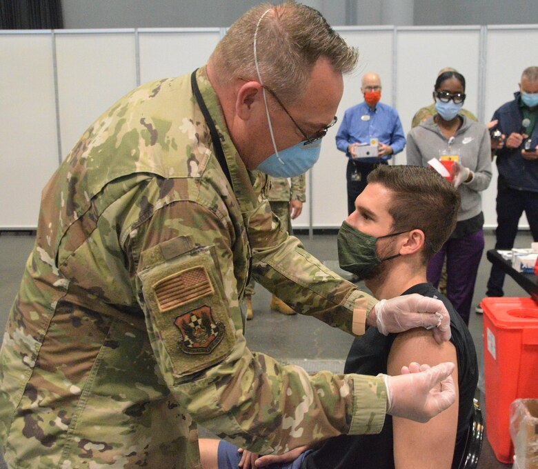 Tom Pescatore, 26, of Manhattan, New York, receives his second Pfizer vaccination from New York Air National Guard, Lt. Col. John Reynolds, a registered nurse assigned to the 105th Air Lift Wing 20, 2021.