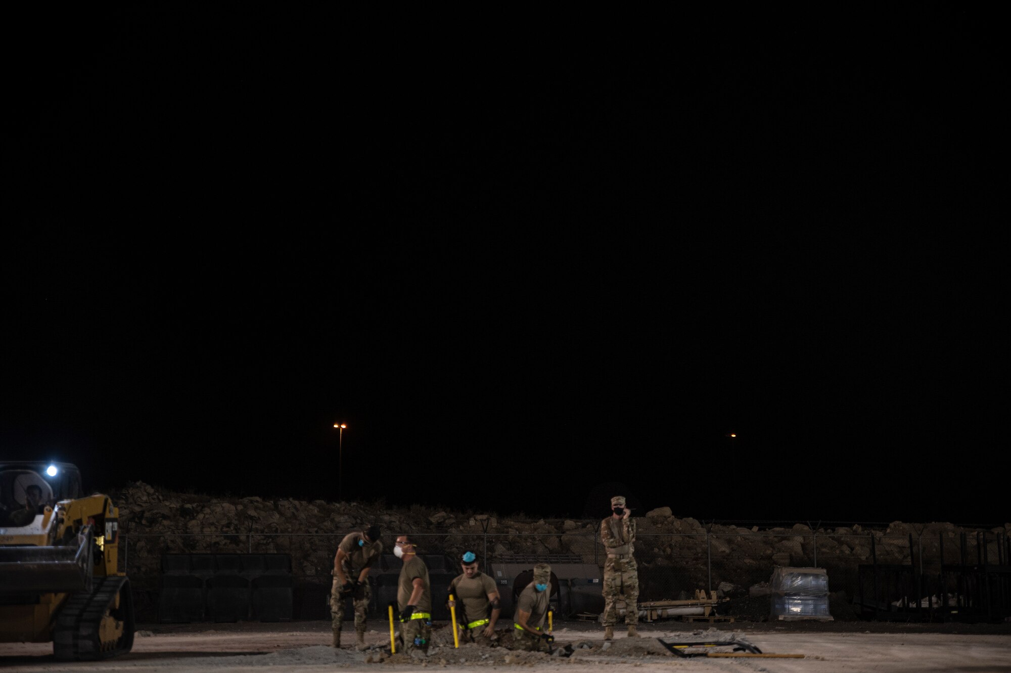 Airmen shovel out dirt from a hole.