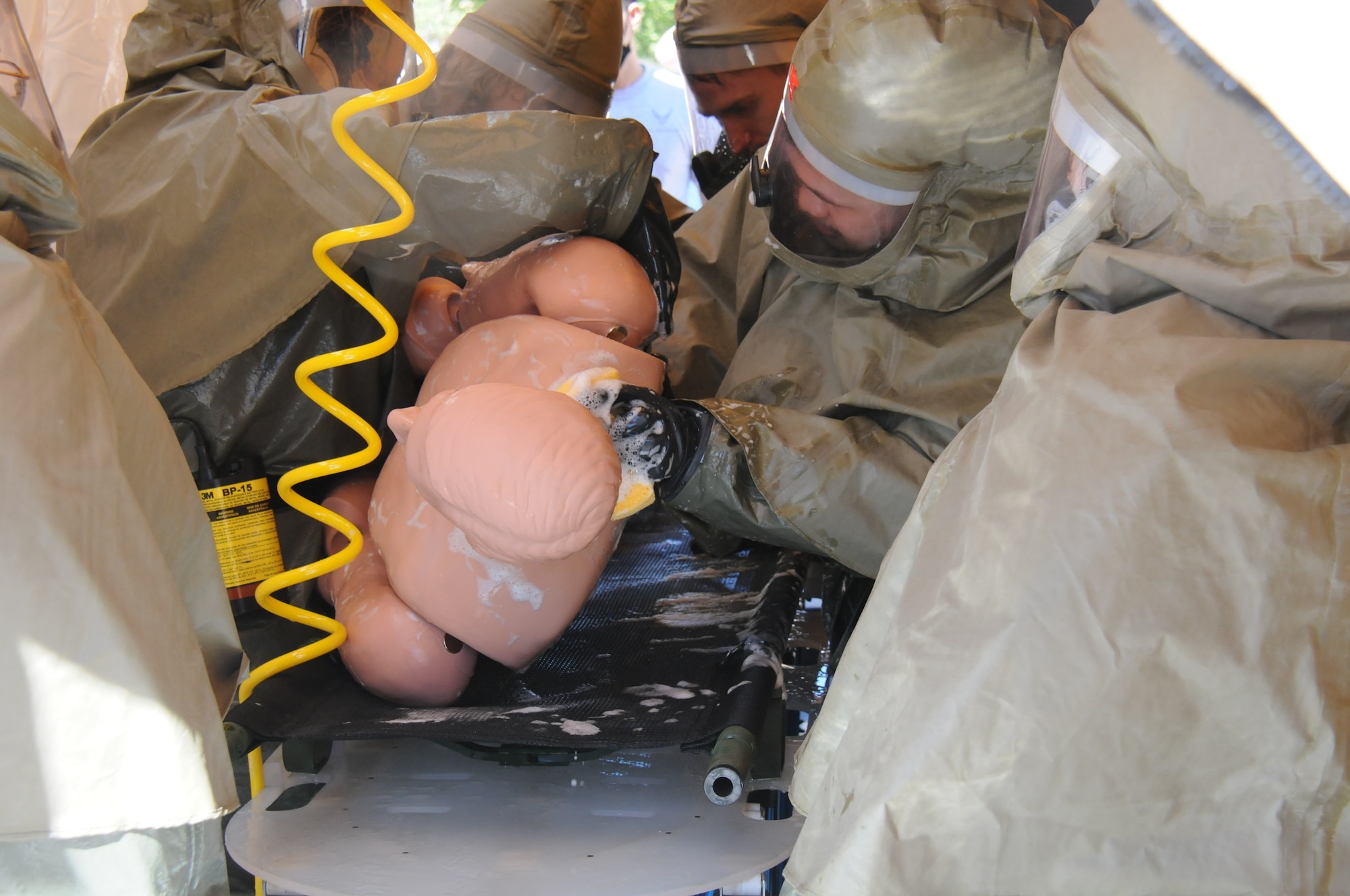 A military medical team decontaminates a simulated patient during an exercise.