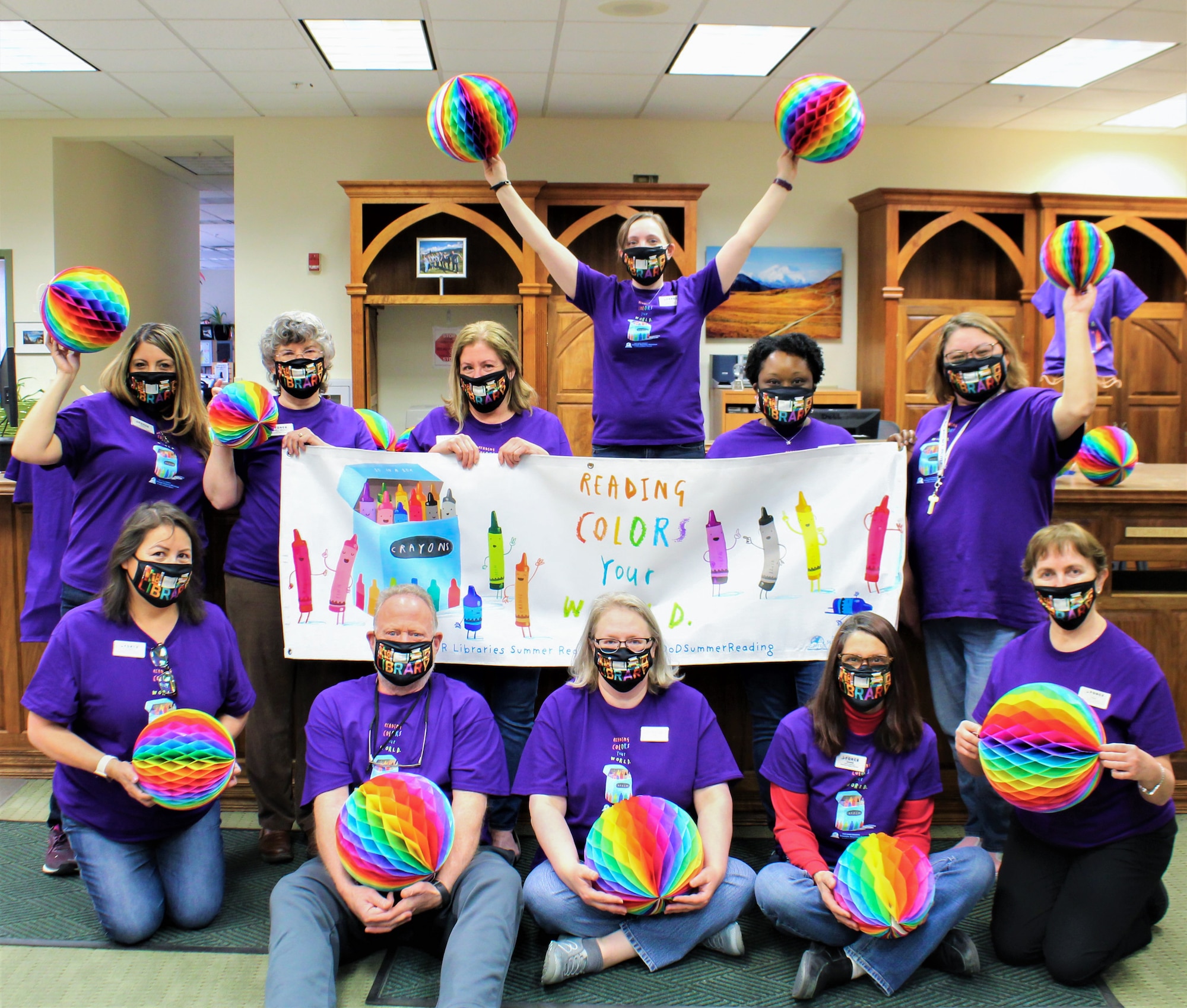 Library staff pose with a banner displaying the theme of this year’s summer reading program at Joint Base Elmendorf-Richardson, Alaska, May 20, 2021. The library will be offering prizes and hosting events throughout the summer to encourage reading. Courtesy Photo.