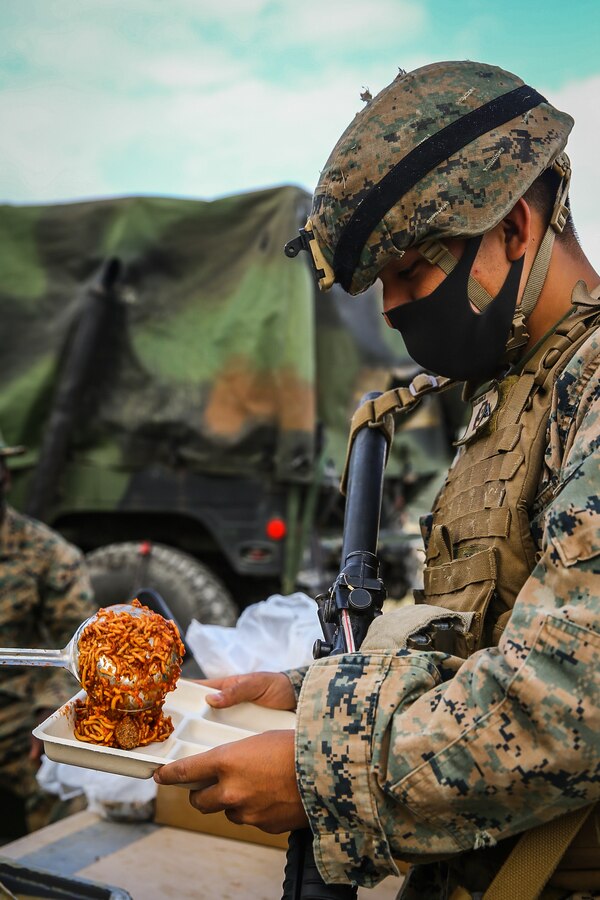 U.S. Marine Corps Lance Cpl. Justin Trejo, electrician with 9th Engineer Support Battalion, 3d Marine Logistics Group, serves hot chow to Marines during exercise Pacific Pioneer, Okinawa, Japan, April 21, 2021. Pacific Pioneer serves as 9th ESB's Marine Corps Combat Readiness Evaluation as well as an opportunity to demonstrate the ability to establish and sustain expeditionary advanced bases with survivable force protection, practice naval integration, and position long range precision fires and tactical logistics nodes across littoral regions in support of naval operations. 3d MLG, based out of Okinawa, Japan, is a forward deployed combat unit that serves as III MEF’s comprehensive logistics and combat service support backbone for operations throughout the Indo-Pacific area of responsibility. Trejo is a native of Long Island, New York. (U.S. Marine Corps photo by Sgt. Hailey D. Clay)