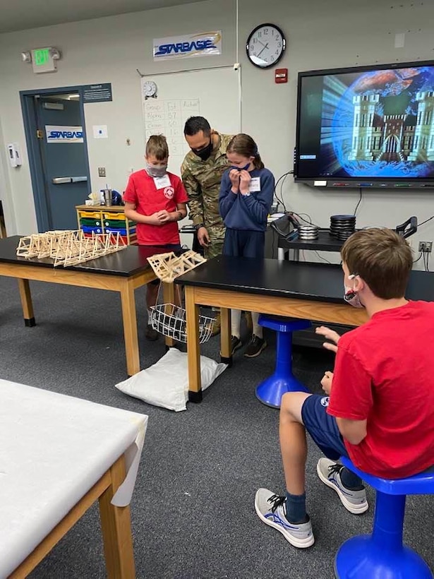 Transatlantic Middle East District Deputy Commander MAJ Eder Ramirez assists students with the weight bearing portion of the bridge build project at a recent STARBASE Academy Winchester presentation.