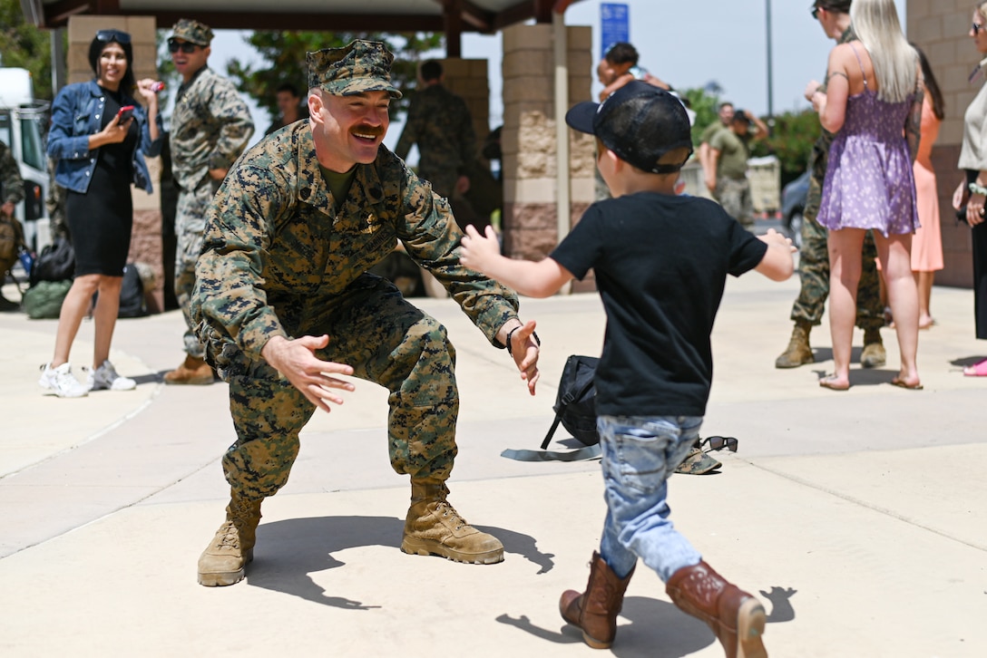 A small boy runs toward a waiting Marine.