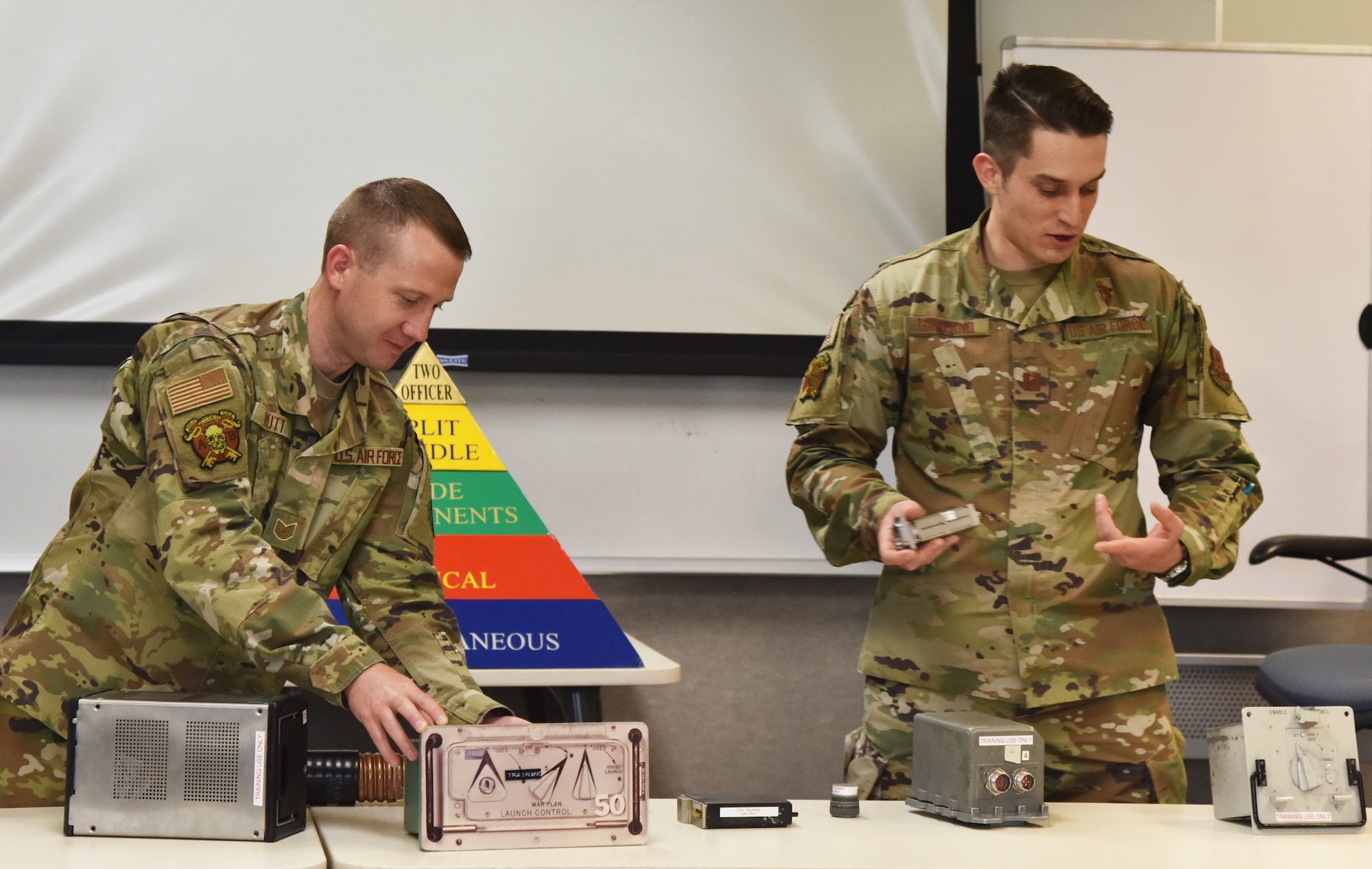 Tech. Sgt. Seth Rutt, 341st Operations Support Squadron nuclear cryptographic controller, left, and Capt. Alexander Garland, 341st OSS nuclear cryptographic operator, examine nuclear launch code training equipment May 19, 2021, on Malmstrom Air Force Base, Mont. In order to launch a missile there are various steps that must be verified by using the shown equipment. (U.S. Air Force photo by Tech. Sgt. Joseph Park)