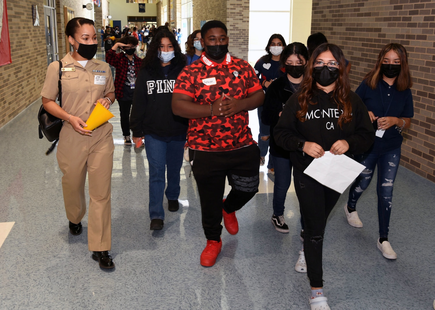 U.S. Navy nurse walking with students, talking to them.