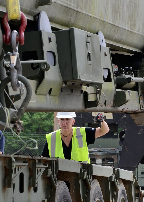 A woman directs material handling equipment movements.