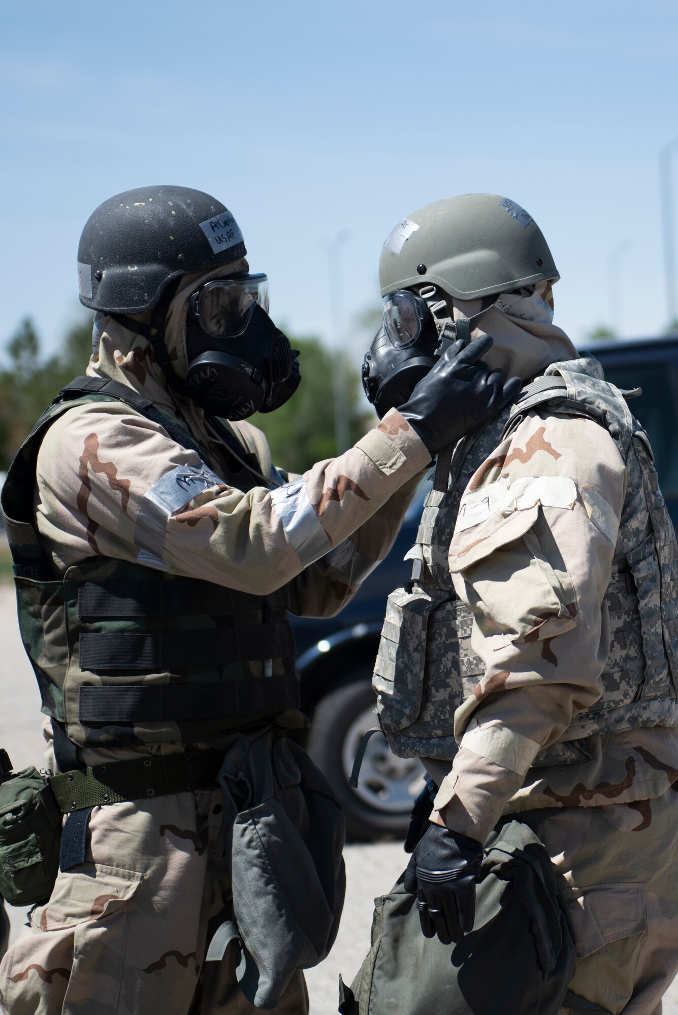 Two Airmen inspect each other's Mission-Oriented Personal Protective Gear.