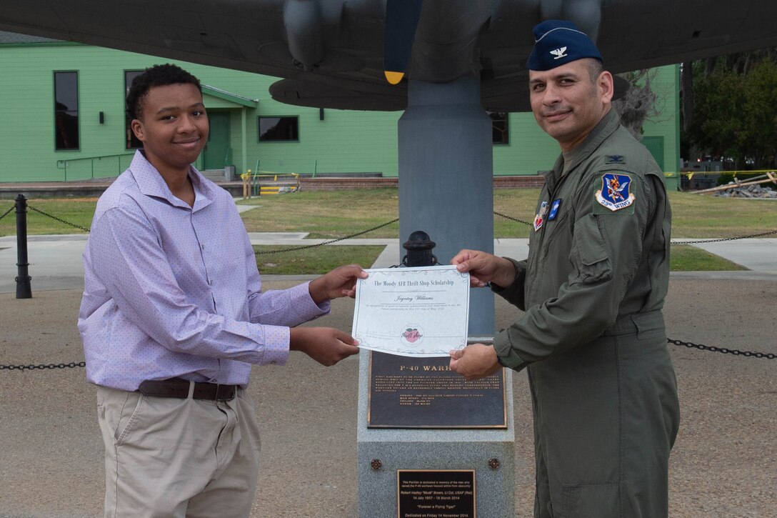 Airmen hands paper to high school student.