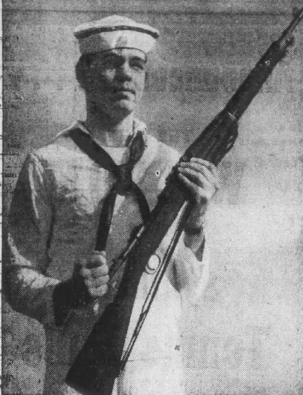 A man wearing a military uniform holds a rifle.