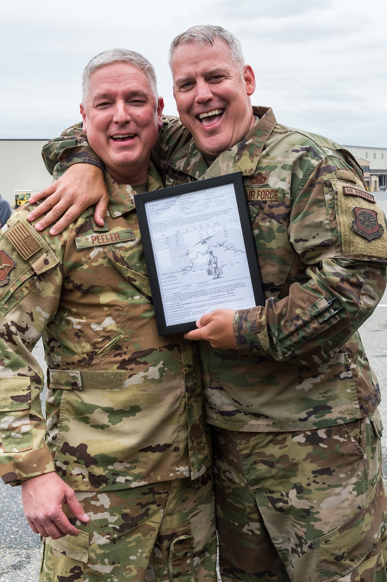 Col. Mike Peeler, left, 436th Operations Group commander, presents Col. Christopher May, 436th Maintenance Group commander, a framed copy of a crew flight authorization at Dover Air Force Base, Delaware, May 24, 2021. After accompanying a local C-17 Globemaster III training flight, May received the traditional “fini flight” hose-down from family, friends and base personnel. May is retiring after serving 33 years in the Air Force. (U.S. Air Force photo by Roland Balik) (This image has been altered for security purposes by blurring out personal identifiable information.)