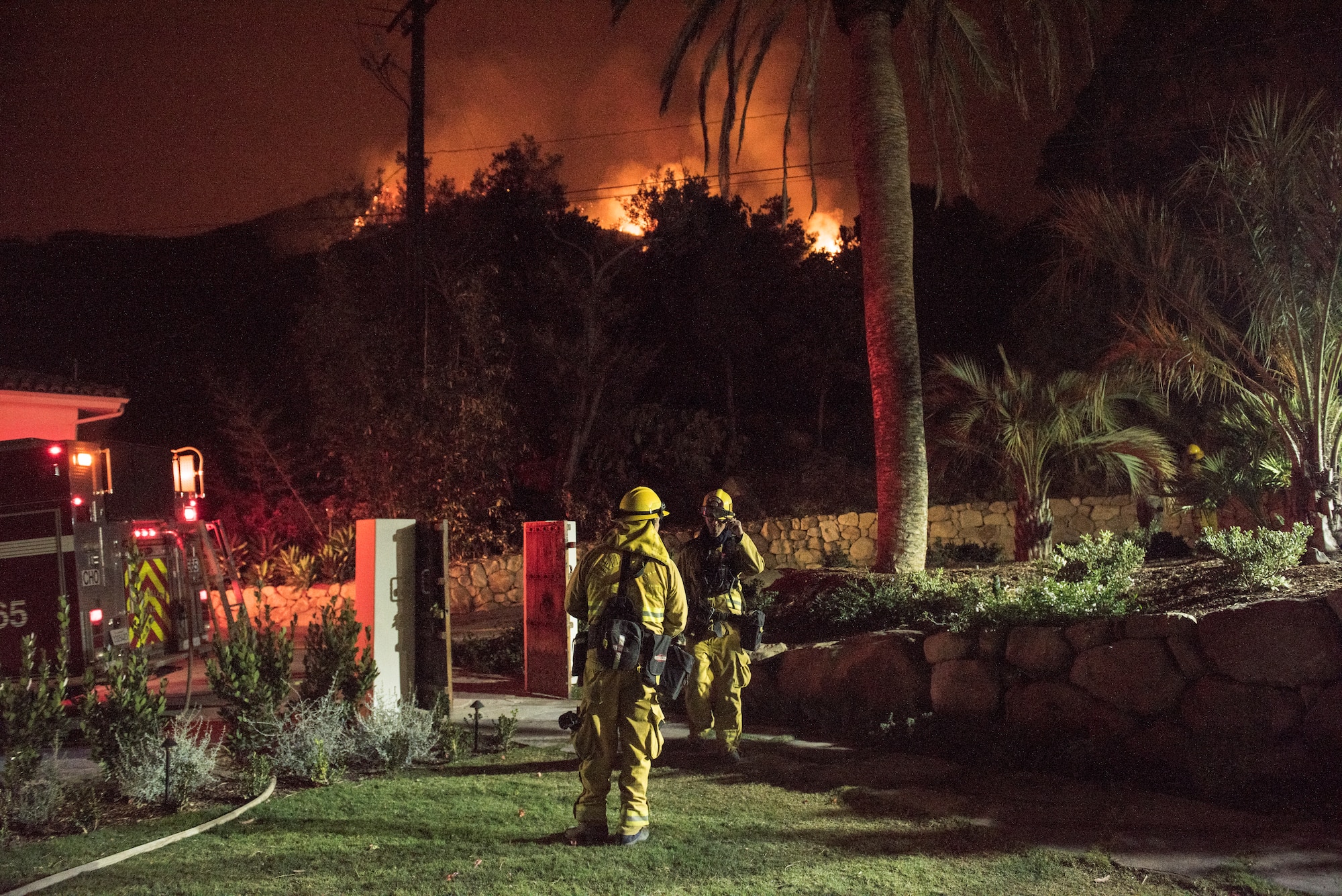 Chino Valley firefighters watch the oncoming flames of the Thomas Fire from the yard of a home in Montecito, California, Dec. 12, 2017. C-130Js of the 146th Airlift Wing at Channel Islands Air National Guard Base in Port Hueneme, carried the Modular Airborne Fire Fighting System and dropped fire suppression chemicals onto the fire's path to slow its advance in support of firefighters on the ground. (U.S. Air Force photo by J.M. Eddins Jr.)
