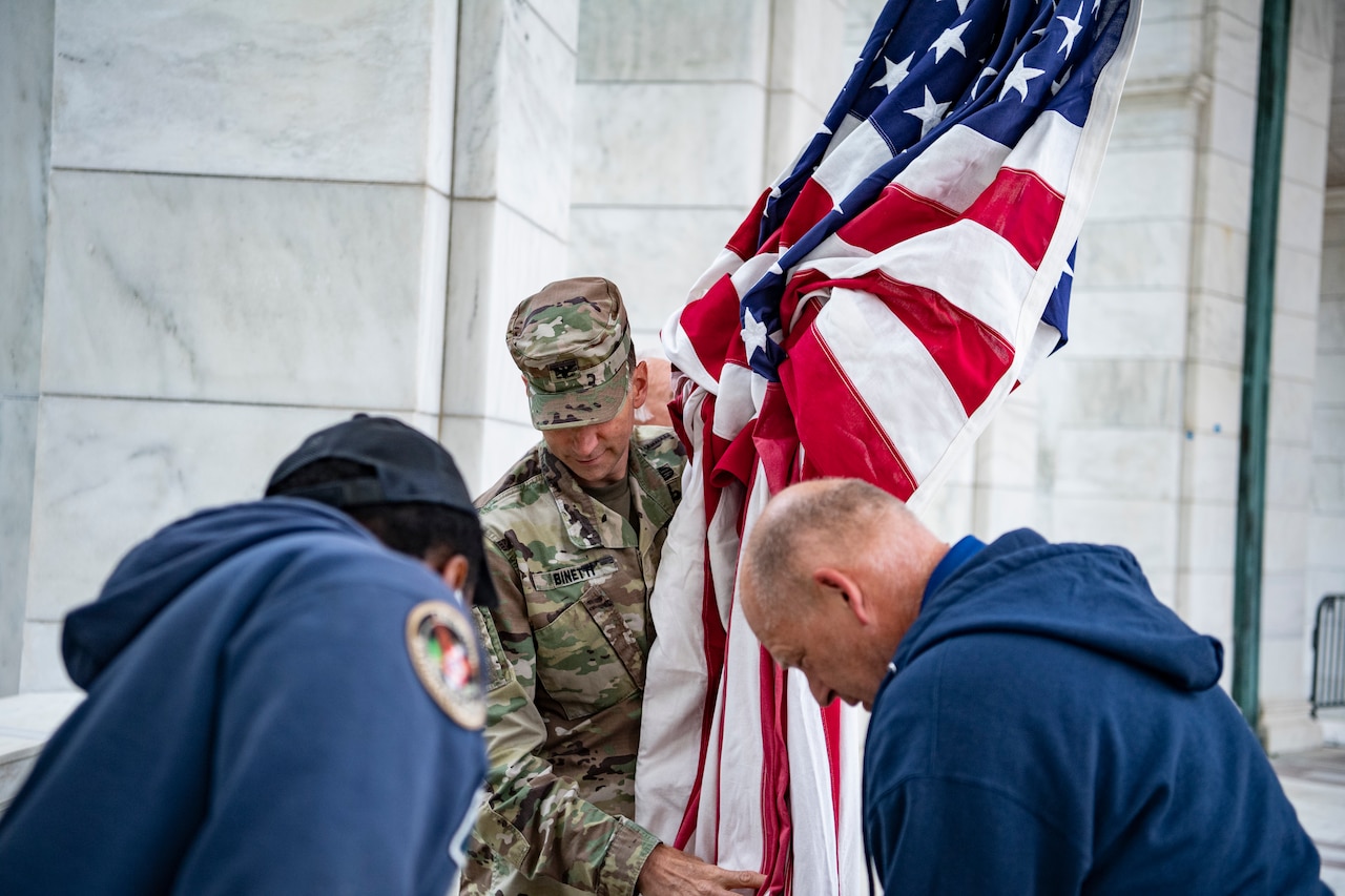 A service member carries an American flag.