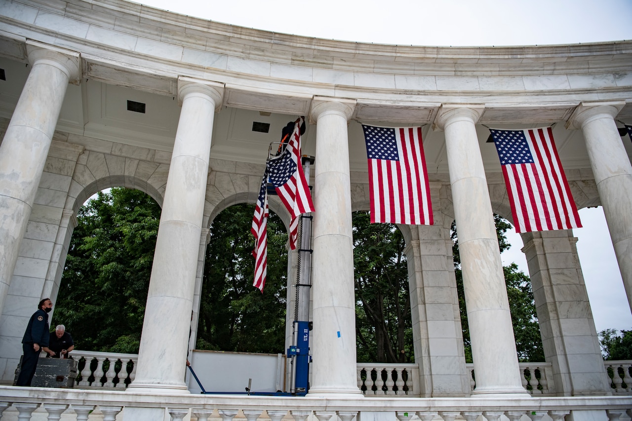 Staff members hang flags on a building.