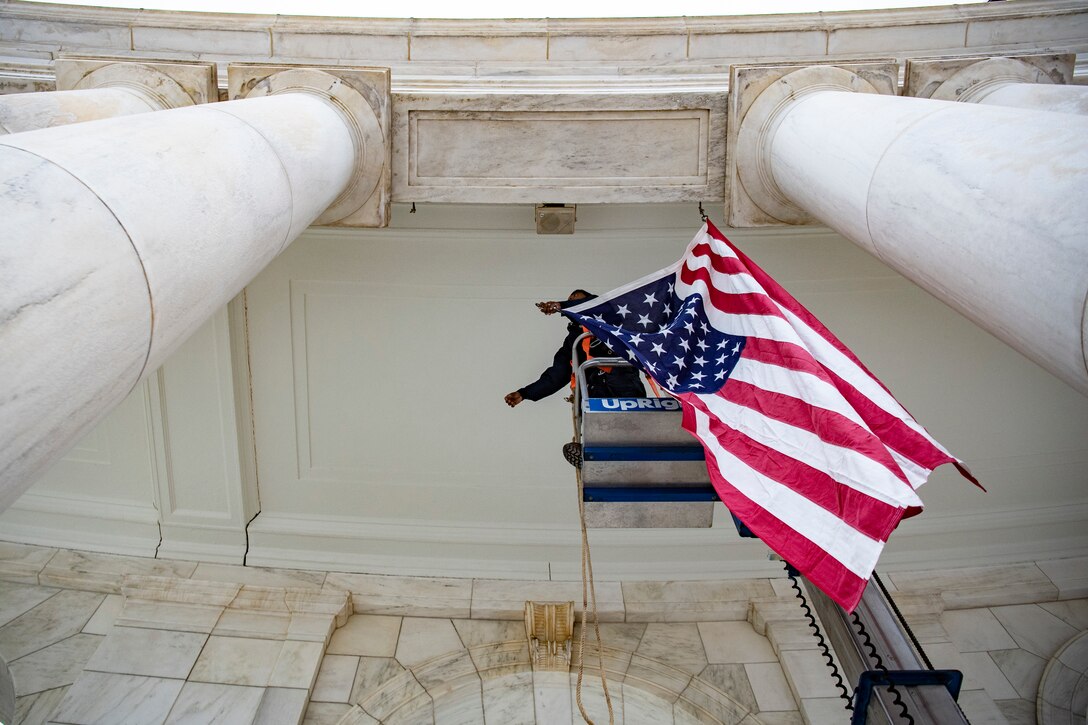 A staff member hangs a flag.