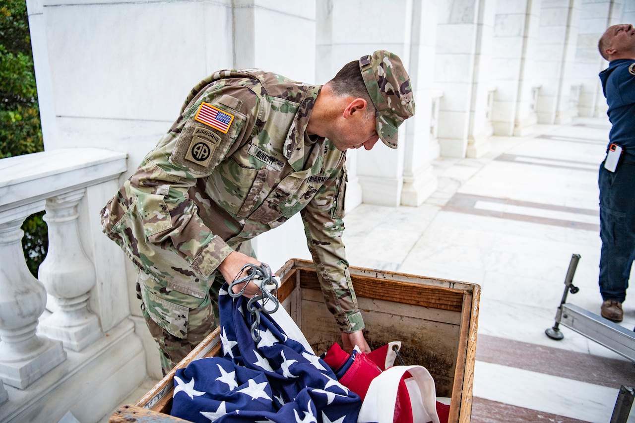 A soldier takes an American flag out of a box.