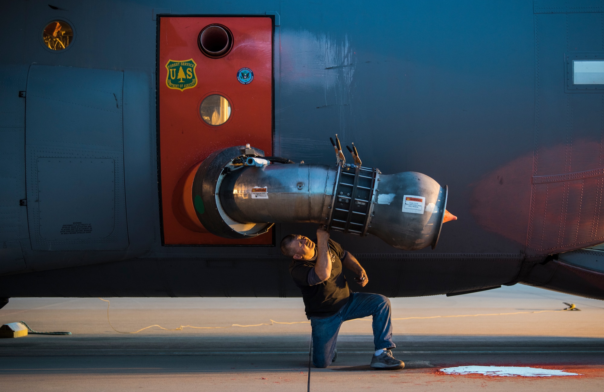 A technician perform repairs on a Modular Airborne Fire Fighting System (MAFFS) in the cargo bay of a C-130J of the 146th Airlift Wing at Channel Islands Air National Guard Base in Port Hueneme, California, Dec. 9, 2017. The MAFFS units, which are owned by the U.S. Forestry Service, can be loaded and made ready for operations in about three hours. A mixture of water and fire-retardant chemicals is deployed through a nozzle attached to an orange door the replaces the paratroop door on the C-130J.(U.S. Air Force photo)