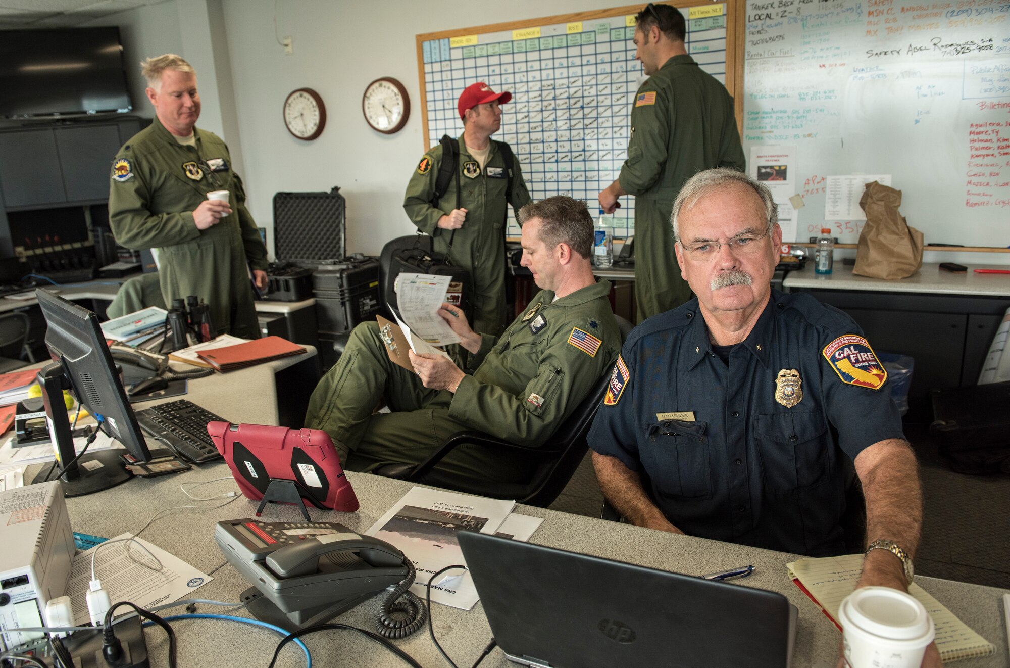 Cal Fire coordinators and the 146th Airlift Wing mission commander, left, work in concert to deploy C-130Js on fire suppression sorties at Channel Islands Air National Guard Base in Port Hueneme, California, Dec. 10, 2017. The aircraft carry the Modular Airborne Fire Fighting System to drop fire suppression chemicals across the path of the Thomas Fire burning in Ventura and Santa Barbara counties in order to slow and contain the massive wildfire. (U.S. Air Force photo by J.M. Eddins Jr.)