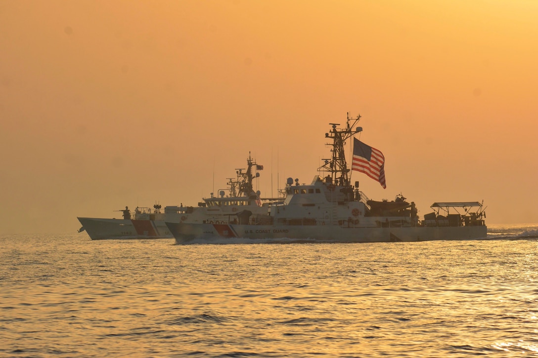 Two Coast Guardships travel through waters.