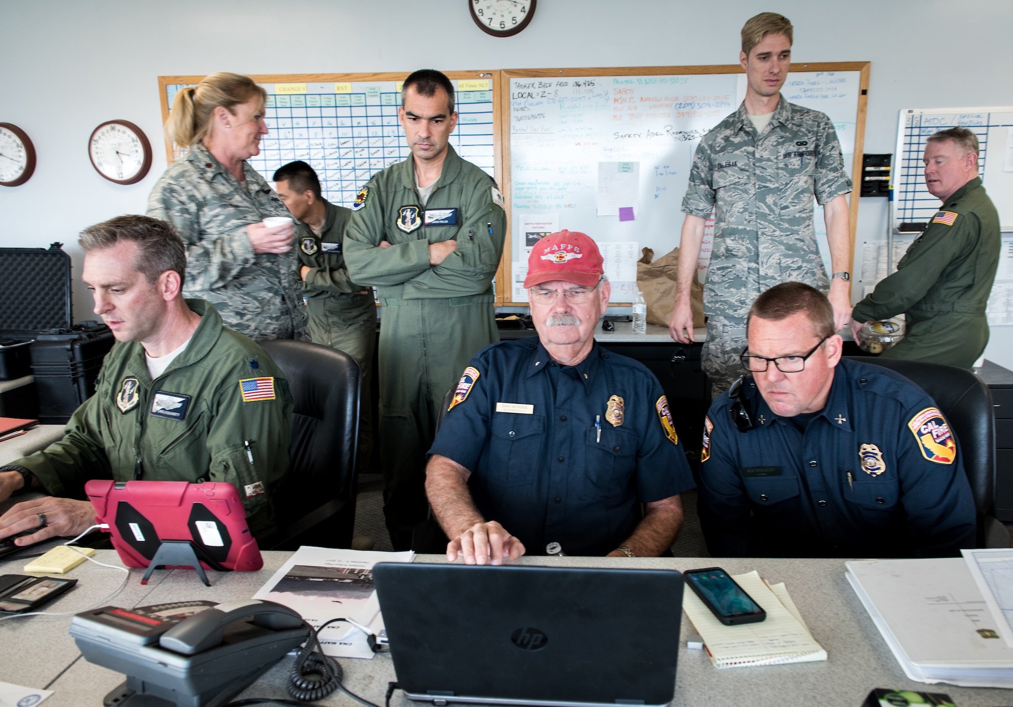 Cal Fire coordinators and the 146th Airlift Wing mission commander, left, work in concert to deploy C-130Js on fire suppression sorties at Channel Islands Air National Guard Base in Port Hueneme, California, Dec. 10, 2017. The aircraft carry the Modular Airborne Fire Fighting System to drop fire suppression chemicals across the path of the Thomas Fire burning in Ventura and Santa Barbara counties in order to slow and contain the massive wildfire. (U.S. Air Force photo by J.M. Eddins Jr.)