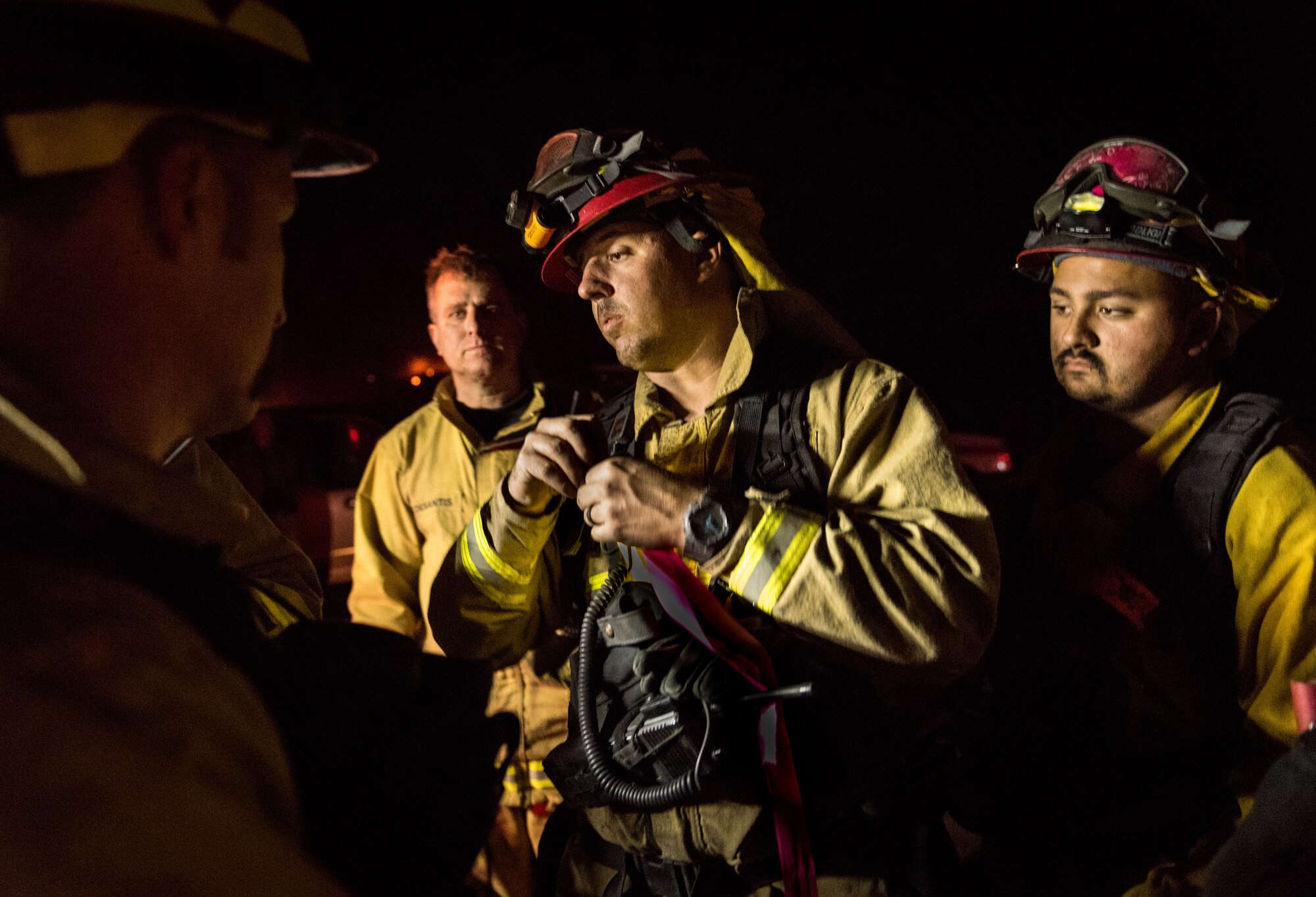 Firefighters assemble before performing a controlled burn to starve the Thomas Fire of fuel, Dec. 10, 2017. Fire crews on the ground dig firebreaks and then call in aircraft, such as the C-130Js of the 146th Airlift Wing at Channel Islands Air National Guard Base in Port Hueneme, California, to drop fire suppression chemicals across the path of wildfires. If winds are calm enough, the firefighters will then burn away foliage in the fire's path to starve it of fuel and stop its advance. (U.S. Air Force photo by J.M. Eddins Jr.)