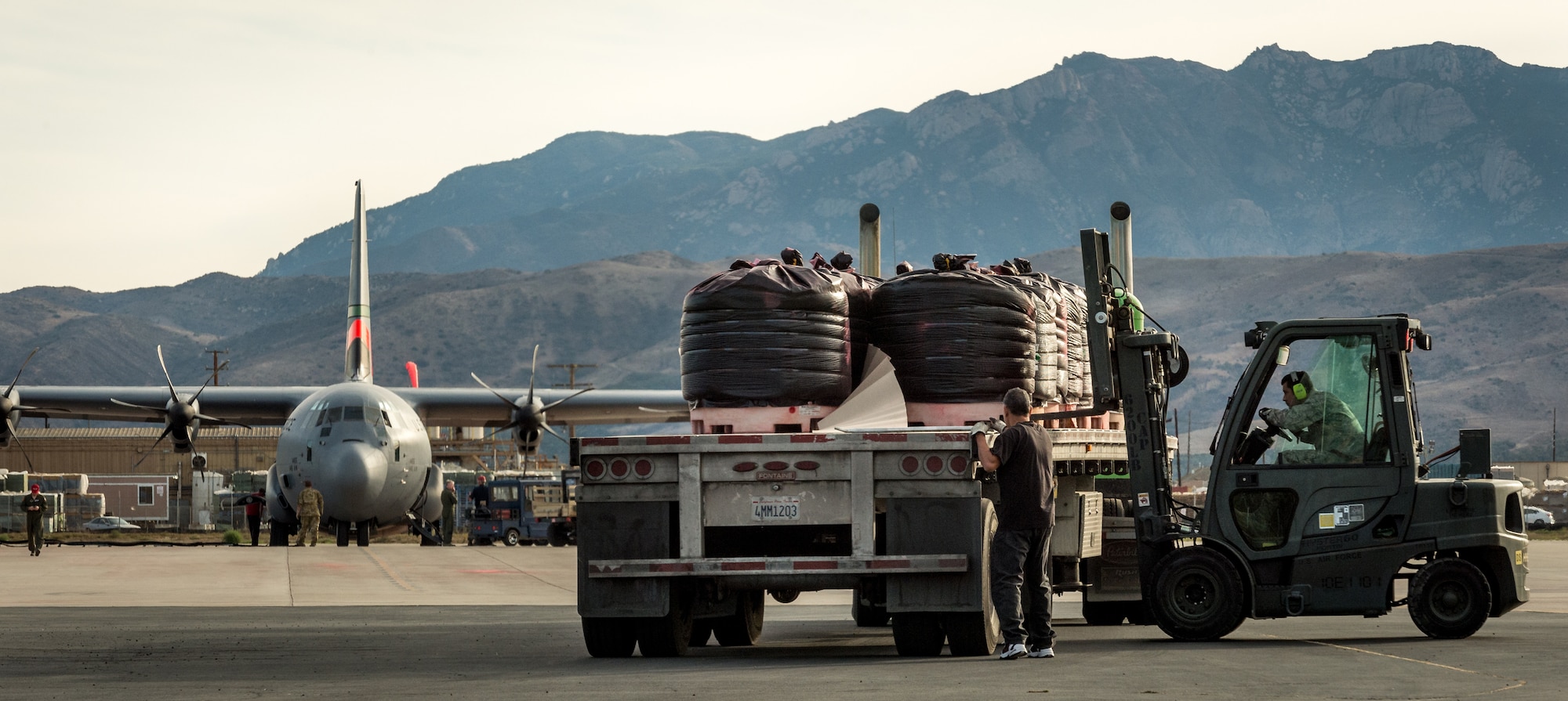 Ground personnel offload fire retardant chemicals on the flightline of the 146th Airlift Wing at Channel Islands Air National Guard Base in Port Hueneme, California, Dec. 10, 2017. Numerous flatbed tractor-trailers arrived each day with the dry chemicals which crews mixed with water and then pumped into the Modular Airborne Fire Fighting Systems carried by the C-130Js.  (U.S. Air Force photo by J.M. Eddins Jr.)