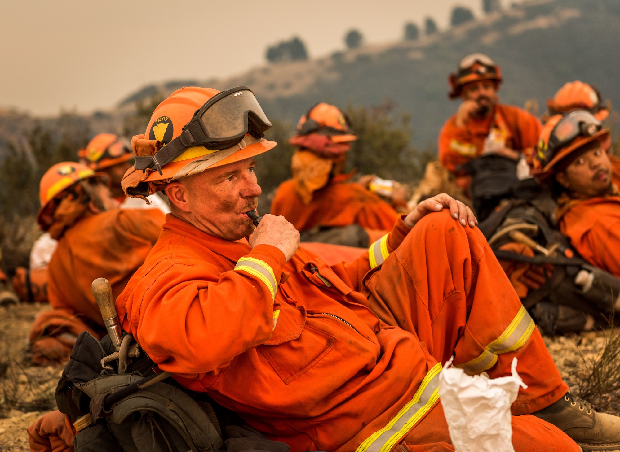 A Cal Fire crew of prison inmates rests after clearing a fire break on a ridge above Santa Barbara, California, Dec. 11, 2017. Inmate crews and bulldozers dug up foliage along ridge lines in the Los Padres National Forest and C-130Js of the 146th California Air National Guard dropped fire retardant chemicals to slow the advance of the Thomas Fire. (U.S. Air Force photo by J.M. Eddins Jr.)