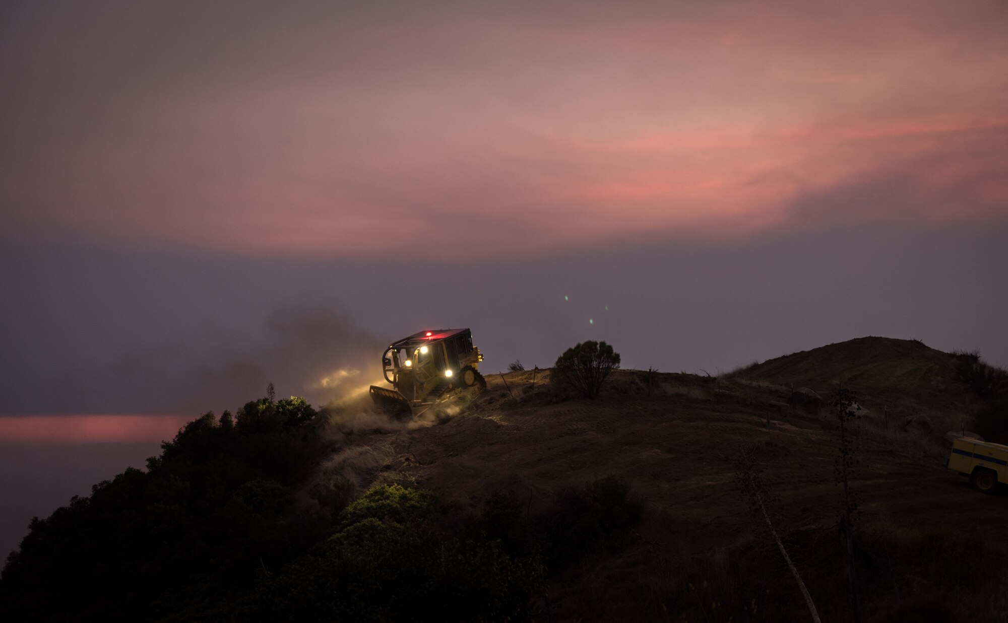 A bulldozer clears away foliage to form a fire-break on a ridge in the Los Padres National Forest above Santa Barbara, California, Dec. 11, 2017. C-130Js of the 146th California Air National Guard Airlift Wing dropped fire retardant chemicals along these fire-breaks to further slow the advance of the Thomas Fire, a large wildfire burning through Ventura and Santa Barbara Counties. (U.S. Air Force photo by J.M. Eddins Jr.)