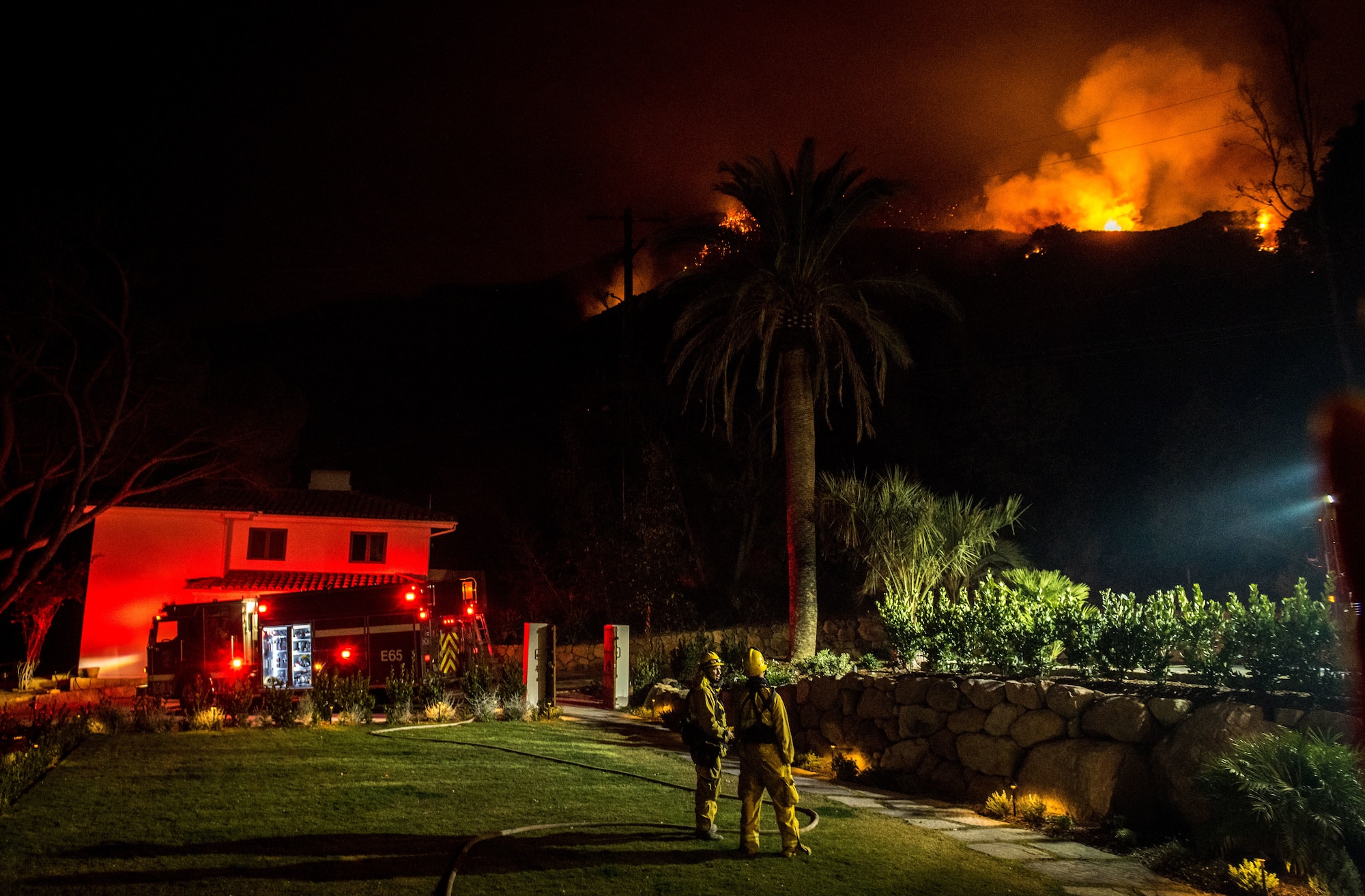 Chino Valley firefighters watch the oncoming flames of the Thomas Fire from the yard of a home in Montecito, California, Dec. 12, 2017. C-130Js of the 146th Airlift Wing at Channel Islands Air National Guard Base in Port Hueneme, carried the Modular Airborne Fire Fighting System and dropped fire suppression chemicals onto the fire's path to slow its advance in support of firefighters on the ground. (U.S. Air Force photo by J.M. Eddins Jr.)
