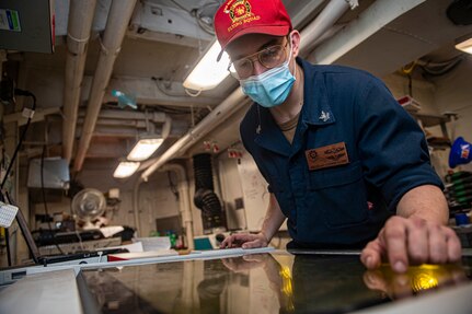 Machinery Repairman 2nd Class Connor Long, from Baton Rouge, Louisiana, uses a laser engraver to engrave lettering into a sign in the repair shop aboard the Nimitz-class aircraft carrier USS Harry S. Truman (CVN 75) during sea trials after completing an extended carrier incremental availability.