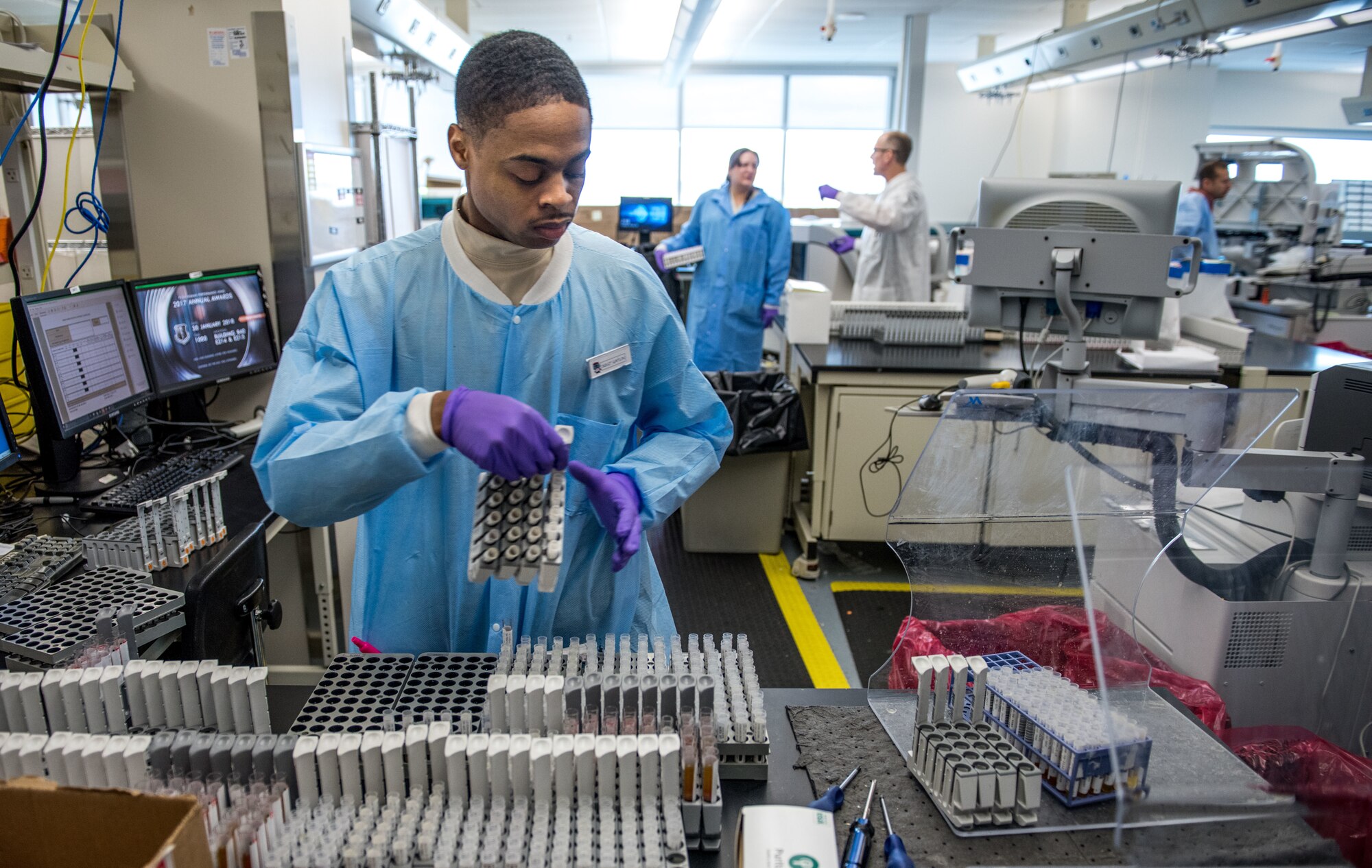 Staff Sgt. Gerald Gatlin prepares serology samples in the immunodiagnostic section of the Epidemiology Laboratory Service, also known as the �Epi Lab,� at the 711th Human Performance Wing�s United States Air Force School of Aerospace Medicine and Public Health at Wright Patterson AFB, Ohio, Jan. 30, 2018. The immunodiagnostic section recently installed an automated testing unit, blue track on left, which is computer controlled to prepare samples and transfer them to the appropriate analyzer for STD screening, status-immune testing or other analyses. The system automatically report results to Department of Defense clinics around the world, usually within 48 hours of a sample being shipped to the lab. (U.S. Air Force photo by J.M. Eddins Jr.)