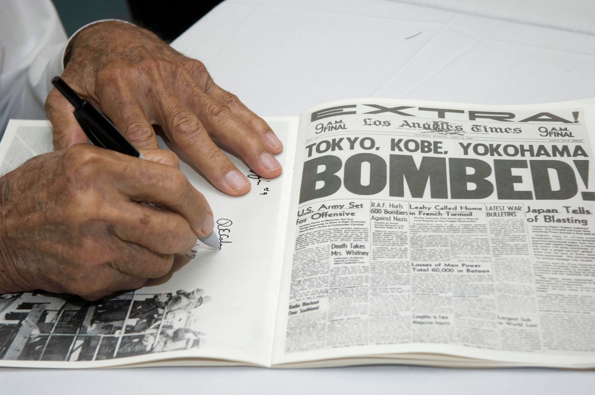 Lt. Col. Robert E. Cole autographs a photograph of his B-25 Mitchell during the Doolittle Raiders homecoming event May 30 in Fort Walton Beach, Fla. Then Lt. Cole was the co-pilot for the first bomber crew to take-off during Doolittle's mission over Tokyo.  (U.S. Air Force photo/Lance Cheung)