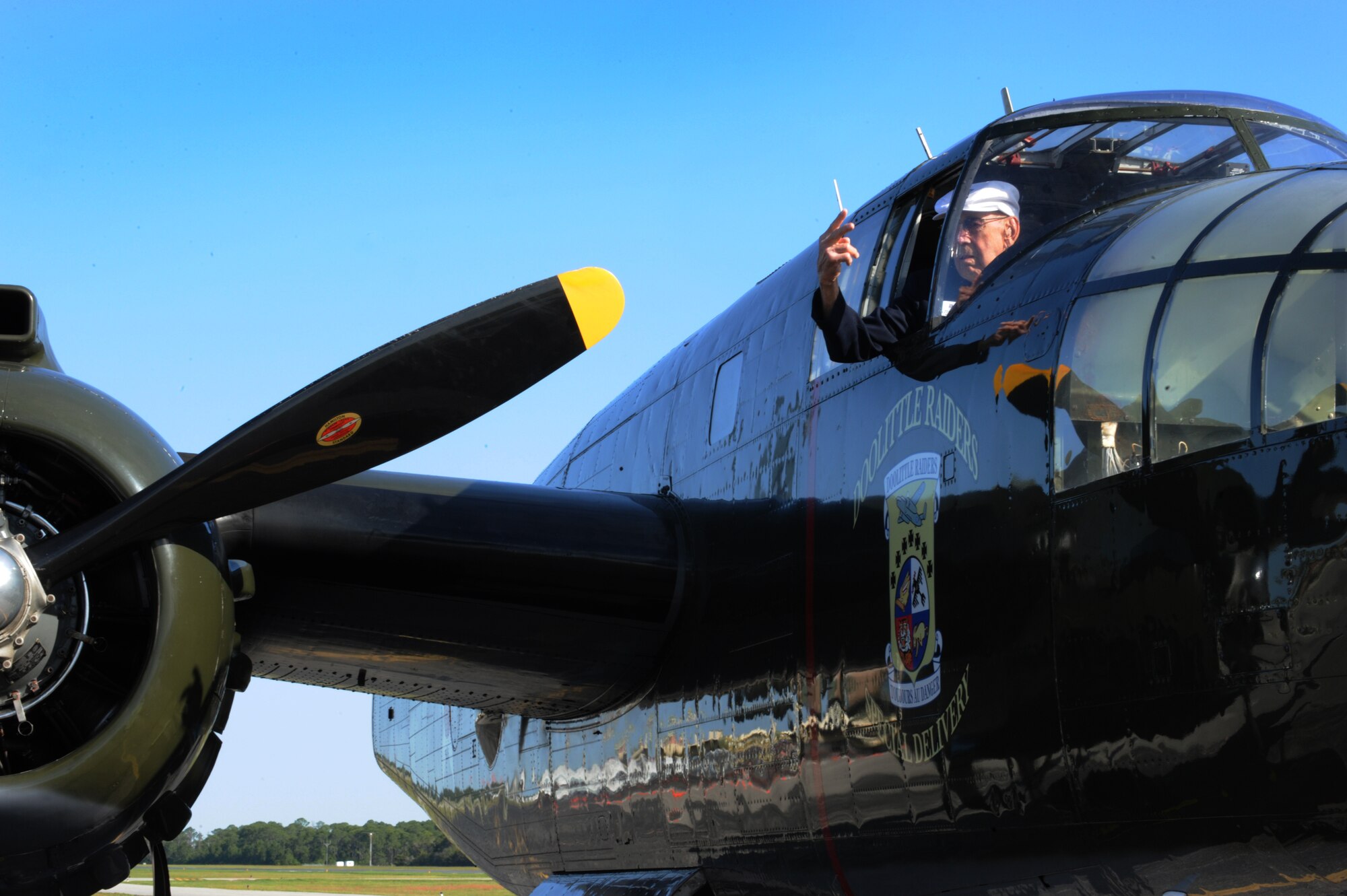Ret. Lt. Col. Dick Cole, Doolittle Raider co-pilot crew 1, signals the start of engine 2 on a B-25 named "Special Delivery", April 20, 2013. (U.S. Air Force Photo by Senior Airman Carlin Leslie)