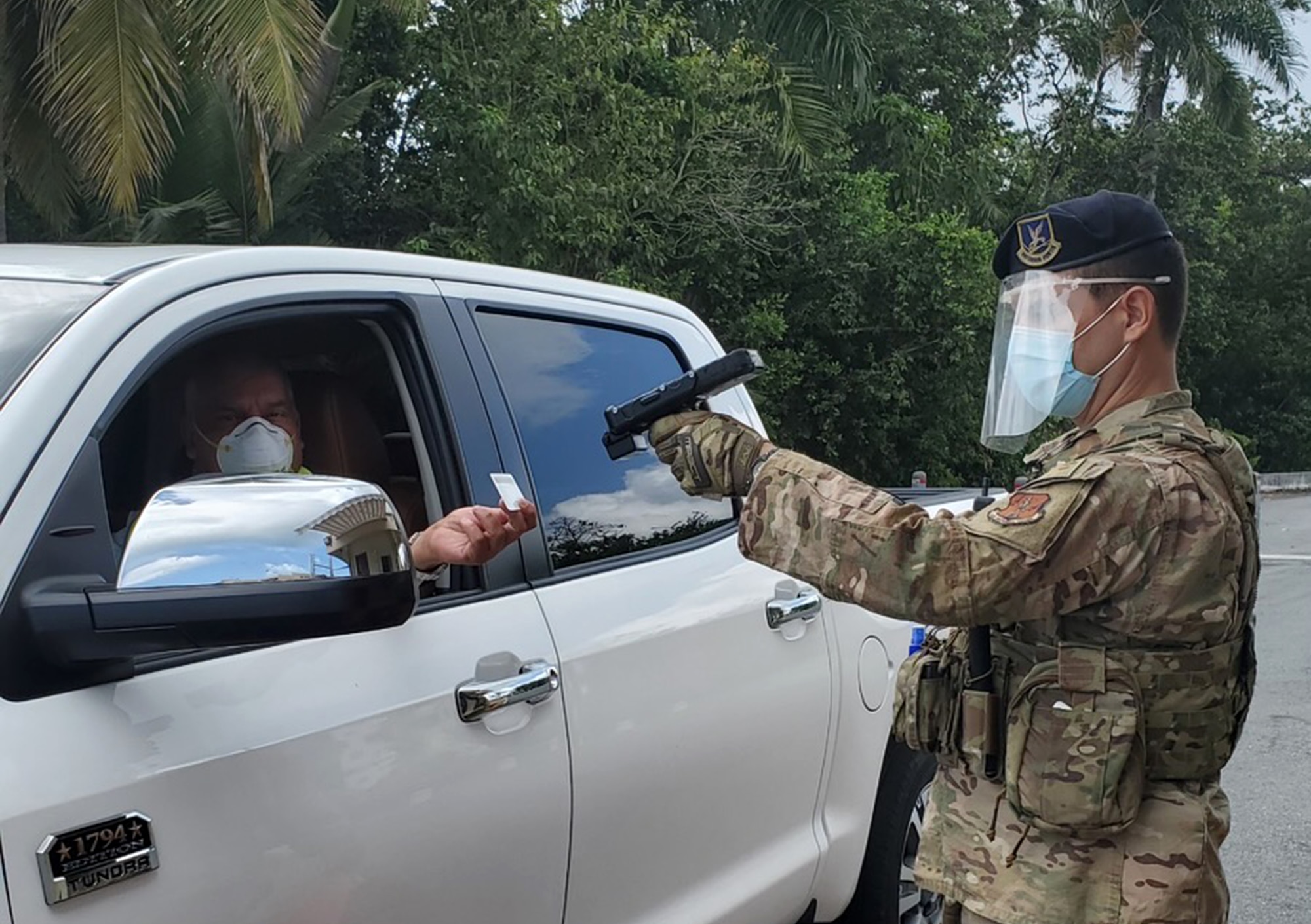 U.S. Air Force Staff Sgt. Eddie Rosario with the 156th Security Forces Squadron checks identification at the gate entrance to Muñiz Air National Guard Base, Puerto Rico Air National Guard, while wearing personal protective equipment, April 9, 2020. The 156th SFS Defenders now have plastic face shields, created by 1st Lt. Jose Arroyo, a cyberspace operations officer with the 156th Communications Flight, to help protect them as they continue their mission while the base is operating under HPCON Delta, in an effort to slow the spread of the novel coronavirus, COVID-19. (U.S. Air National Guard courtesy photo)